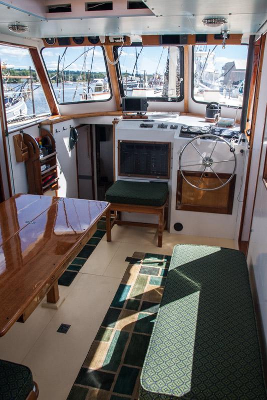 Interior of 1996 Custom Bolger PH Shoal-draft Ketch with helm, seating, and table.