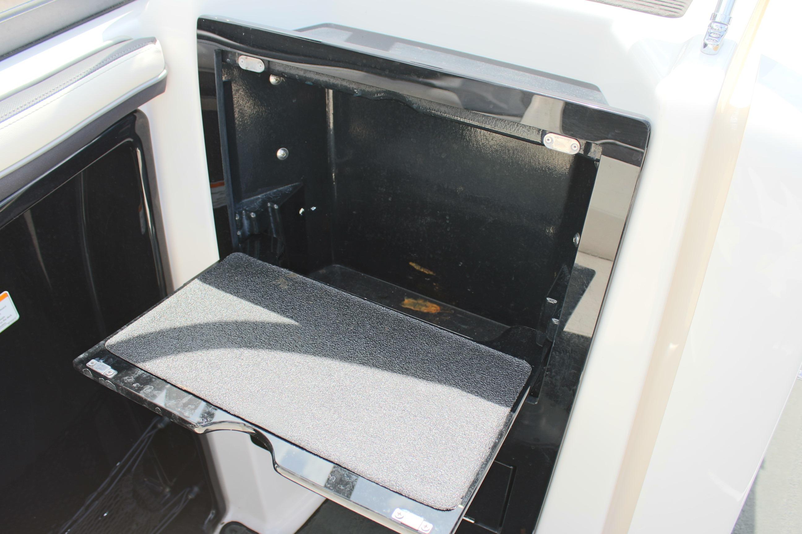 2016 Yamaha Boats 242 Limited S storage compartment with open door and fold-out shelf.
