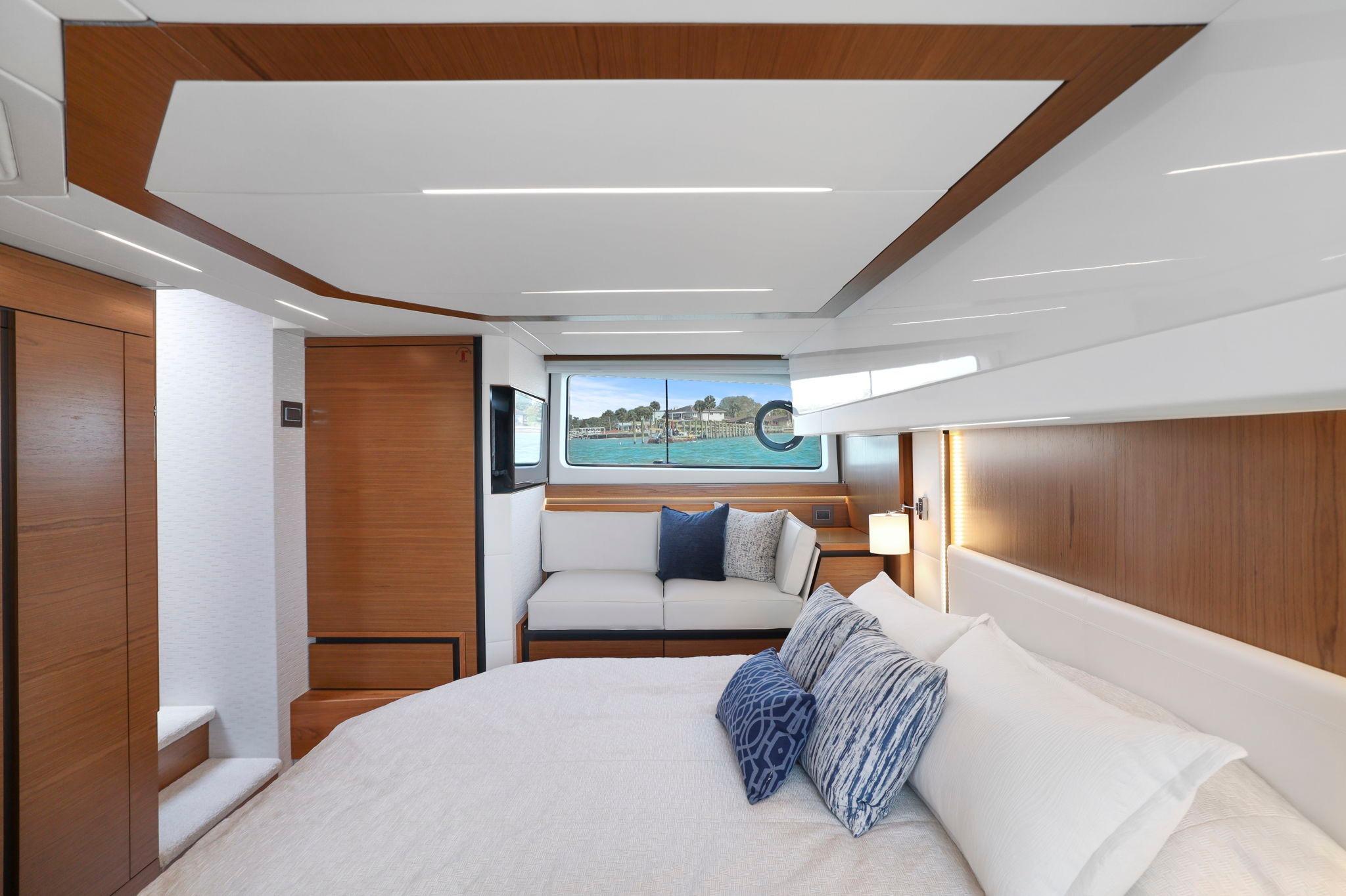Luxurious interior of 2023 Tiara Yachts C49 Coupe with elegant wood finishes and plush bedding.