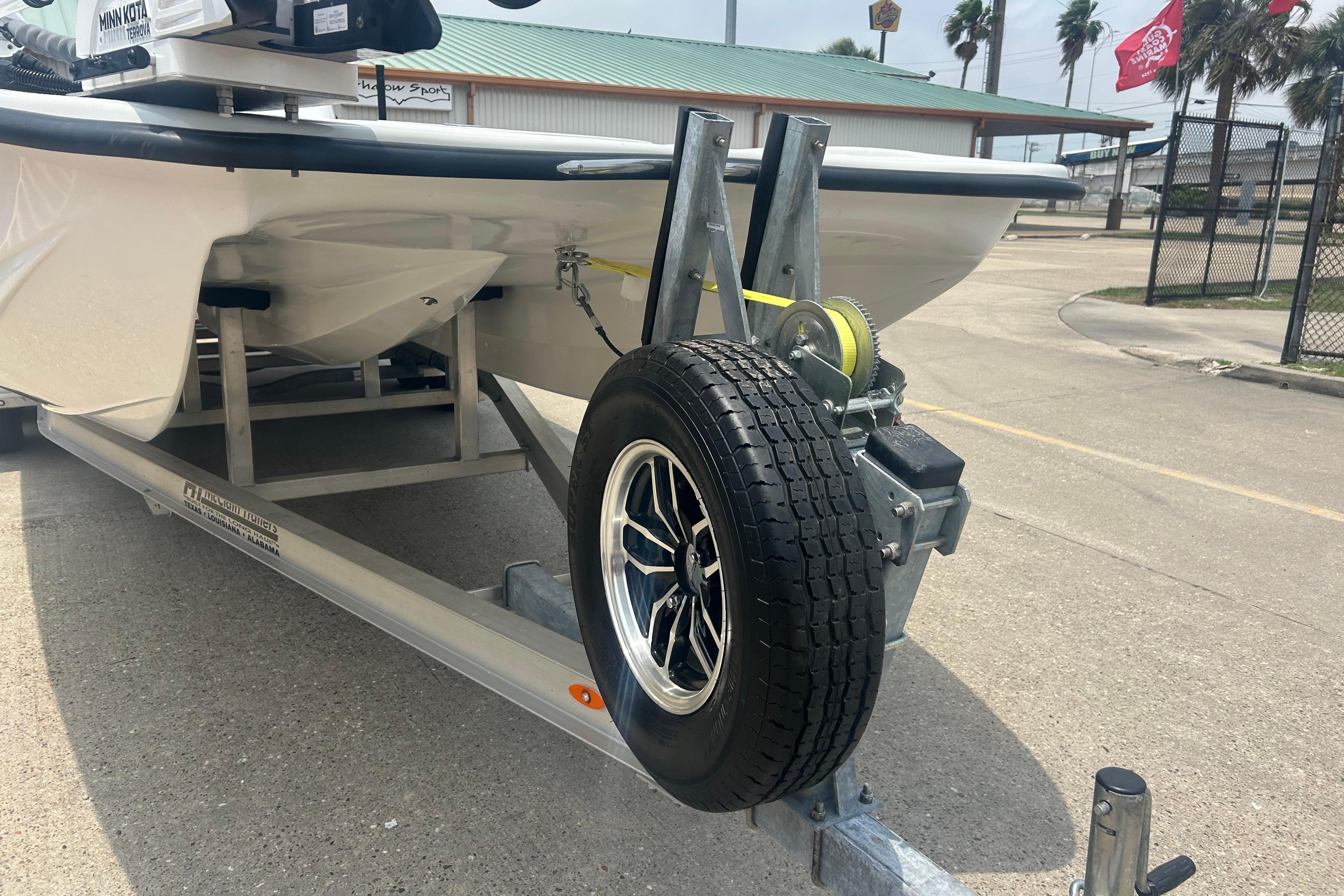 2025 Skuta 24 boat on trailer with spare tire, parked outdoors.