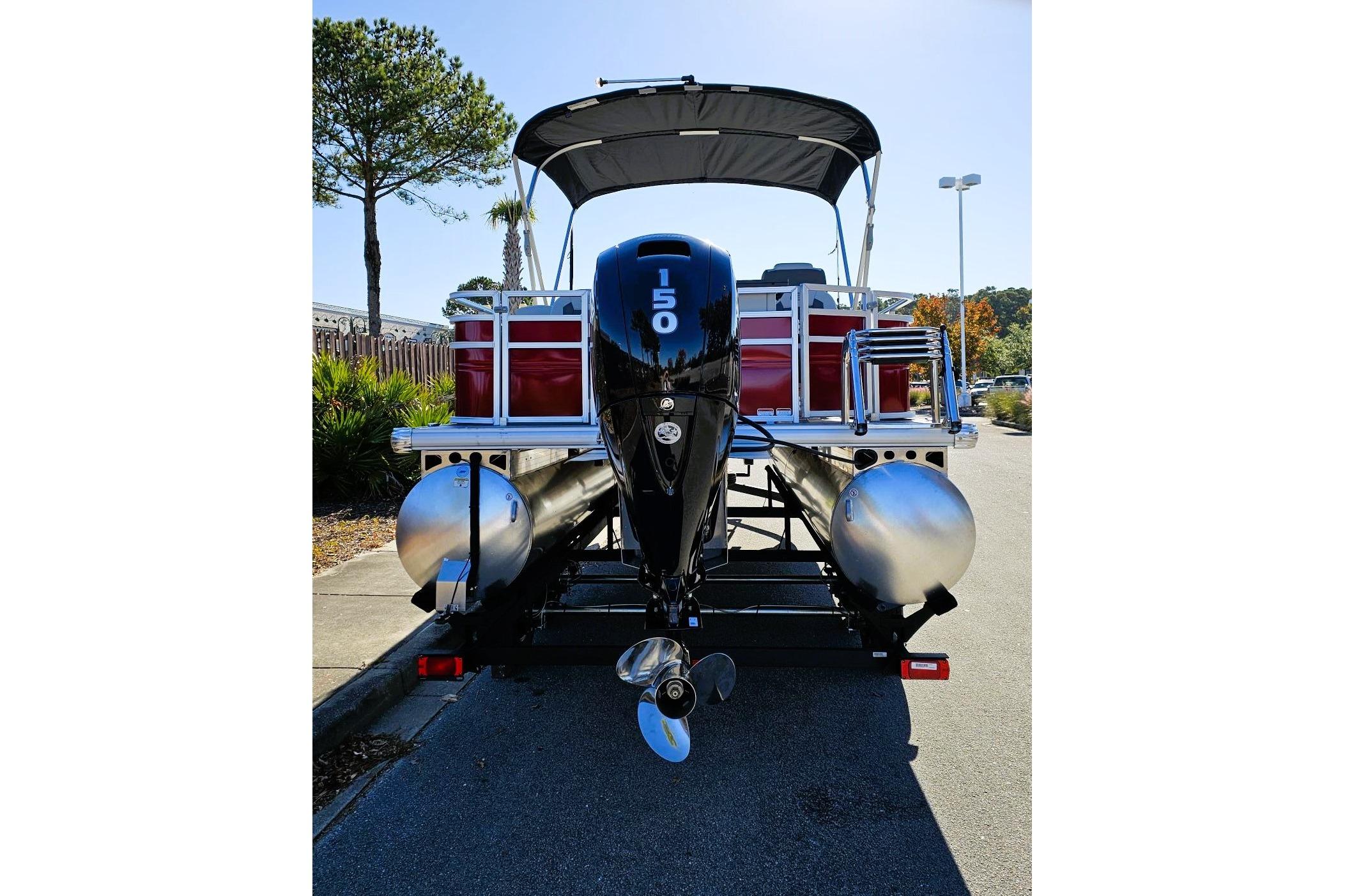 2026 Sun Tracker Fishin' Barge 22 DLX pontoon boat with 150 HP engine, parked on trailer.