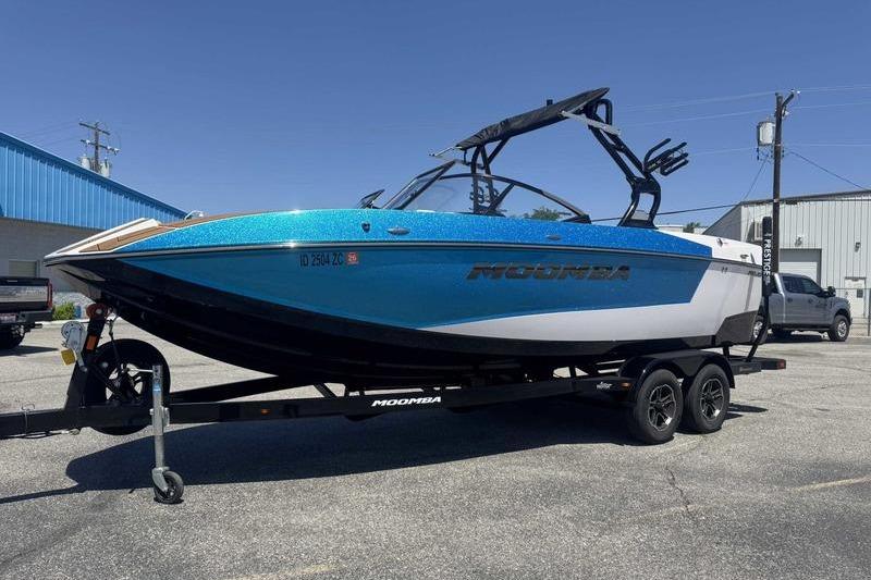 2023 Moomba Mojo Pro boat on trailer, vibrant blue and white design, parked outdoors.