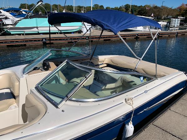 2000 Sea Ray 210 Bow Rider boat docked with blue bimini top and beige interior.