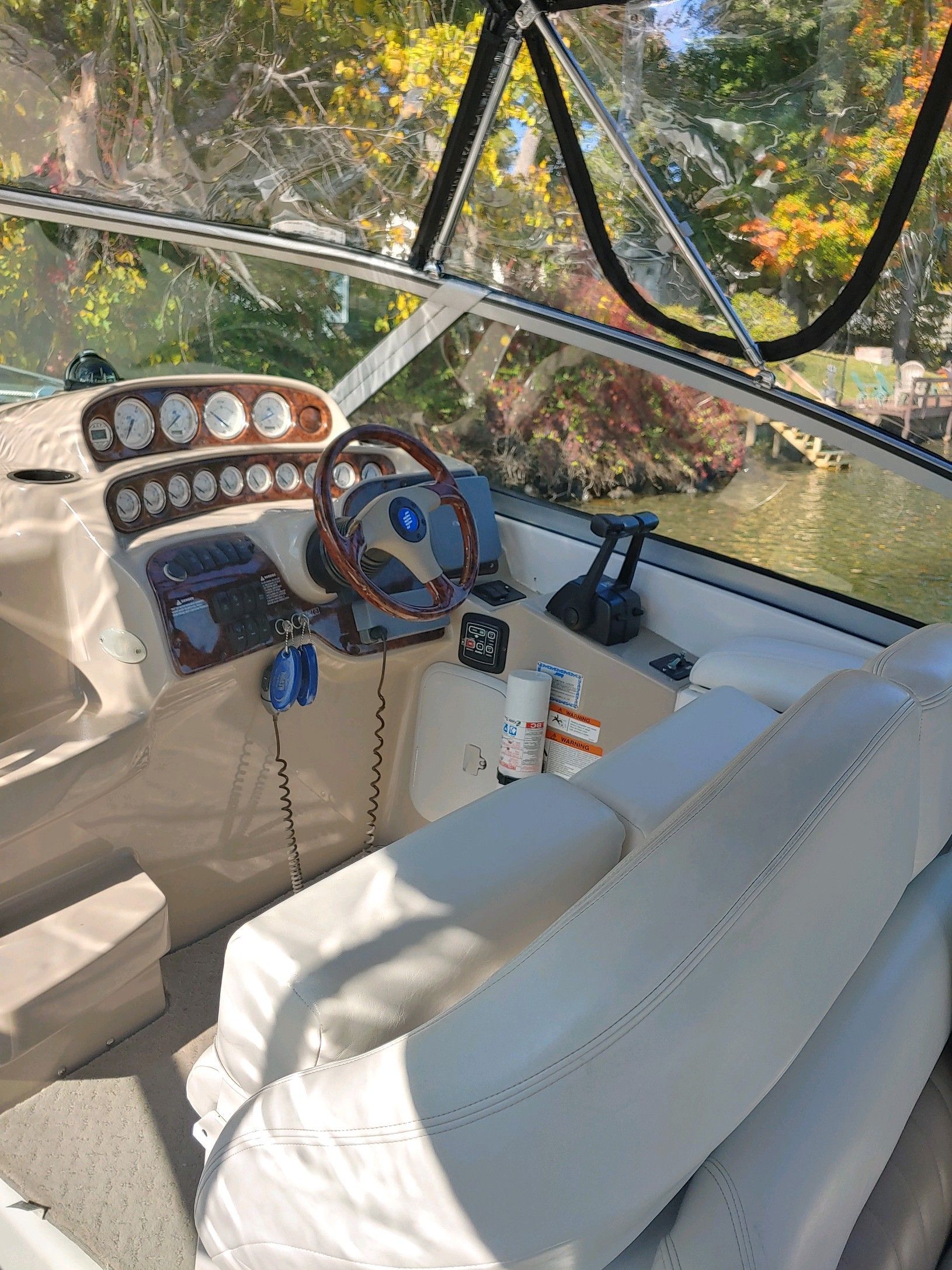 The cockpit of a boat with a wooden steering wheel and instrument panels.