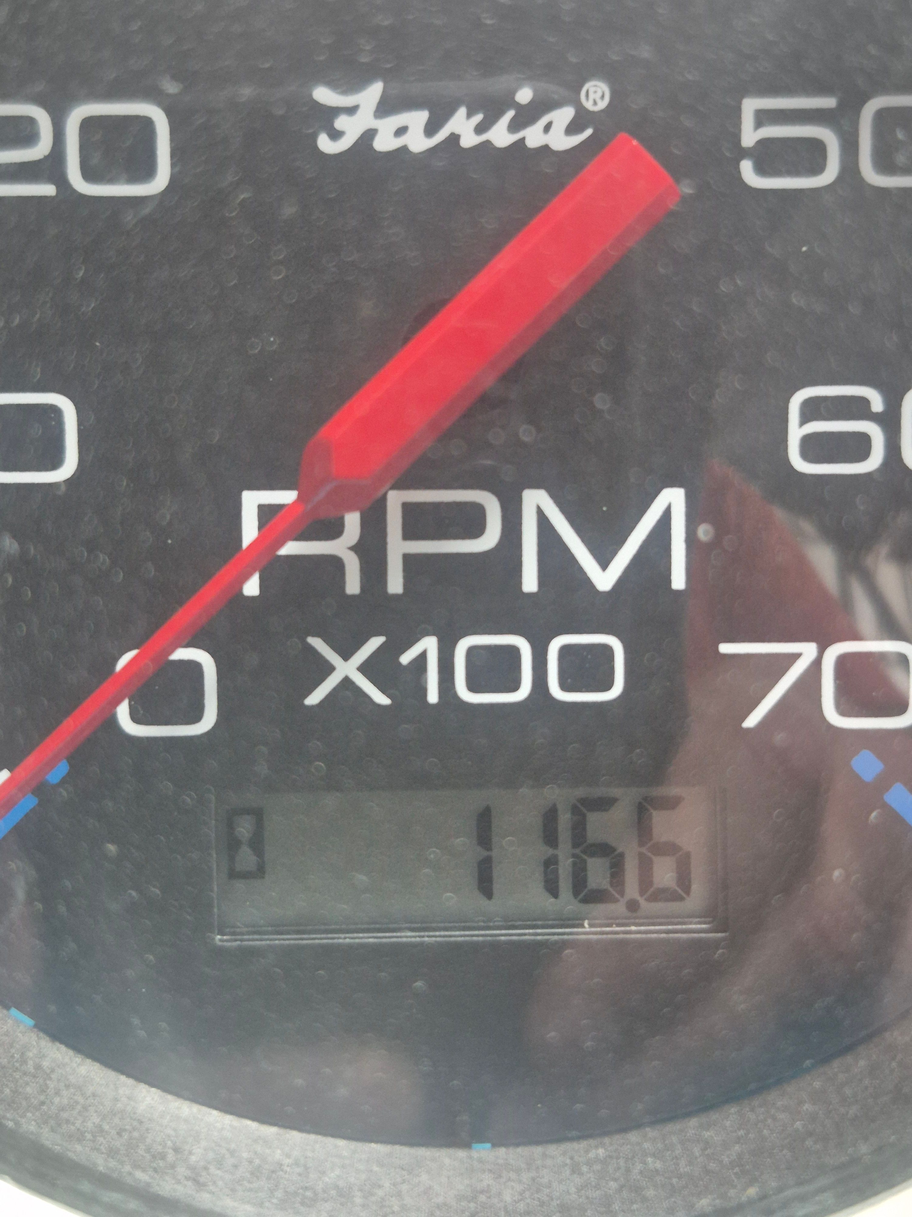 Close-up of a tachometer with a red needle at 1166 RPM.