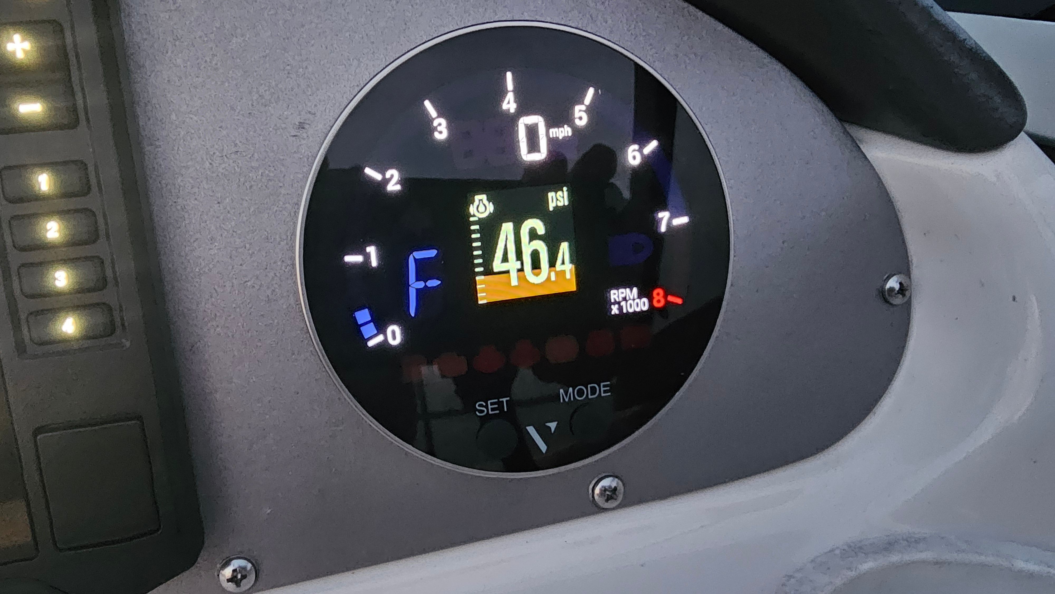 Close-up of a boat instrument with digital display and tachometer.