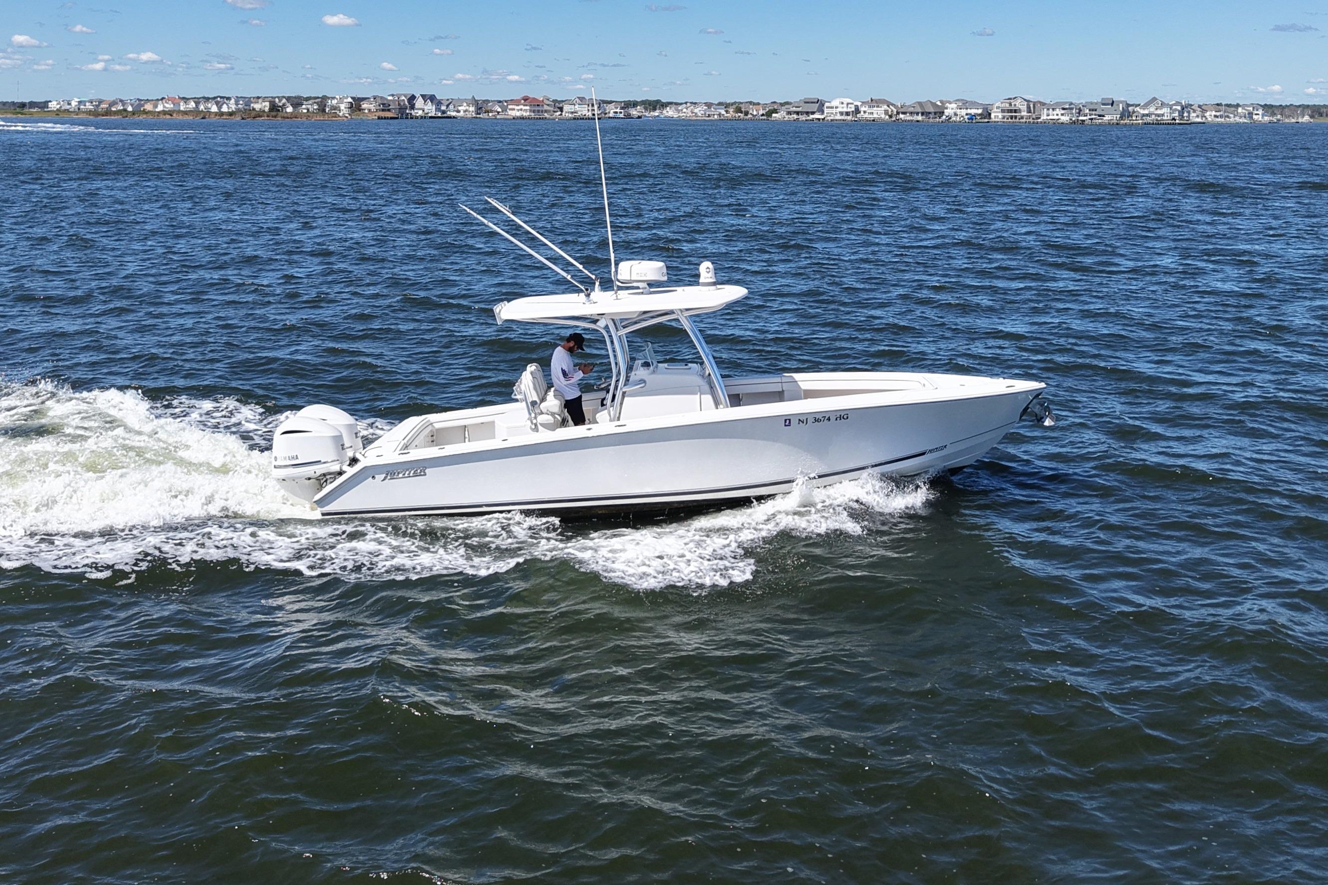 2014 Jupiter 30 FS boat cruising on open water near coastal homes.