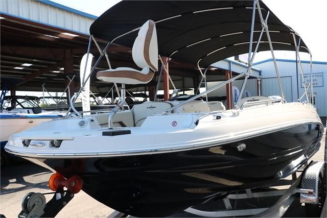 A 2022 Stingray 212 SC boat with a black hull and sunshade, on a trailer.