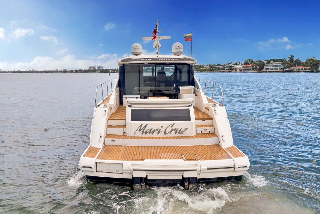 2012 Fairline Targa 58 yacht on water, rear view, with wooden deck and flags.