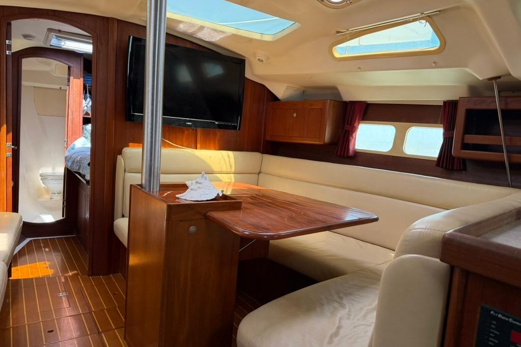 Interior of a 2002 Hunter 410 sailboat with cozy seating and wooden finishes.