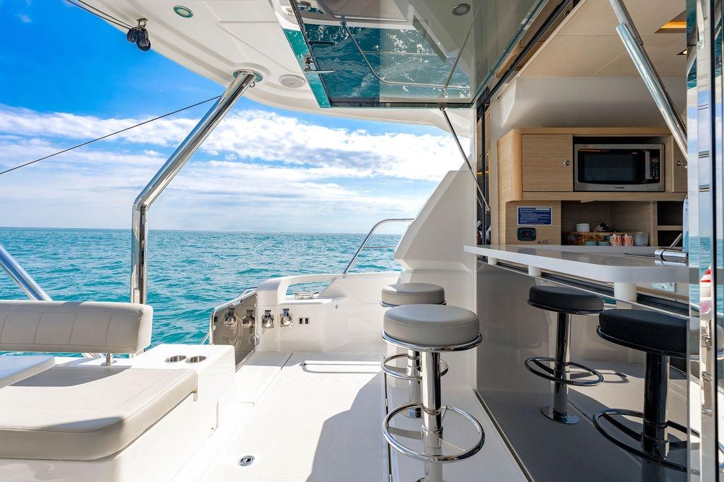 Luxurious 2024 Aquila 44 Yacht interior with ocean view, featuring modern seating and kitchenette.