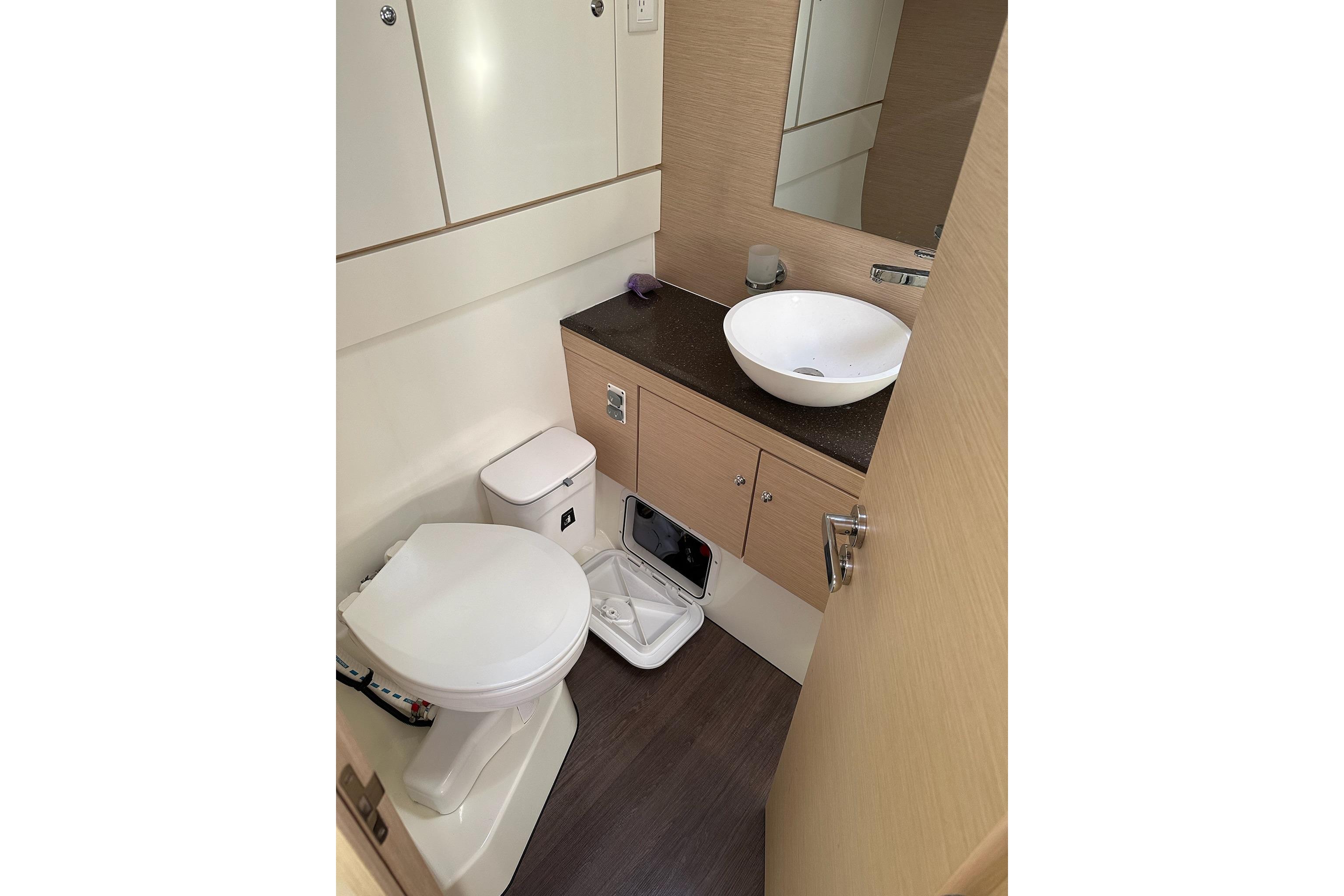 Modern bathroom in 2018 Jeanneau 51 yacht with sink, toilet, and storage cabinets.