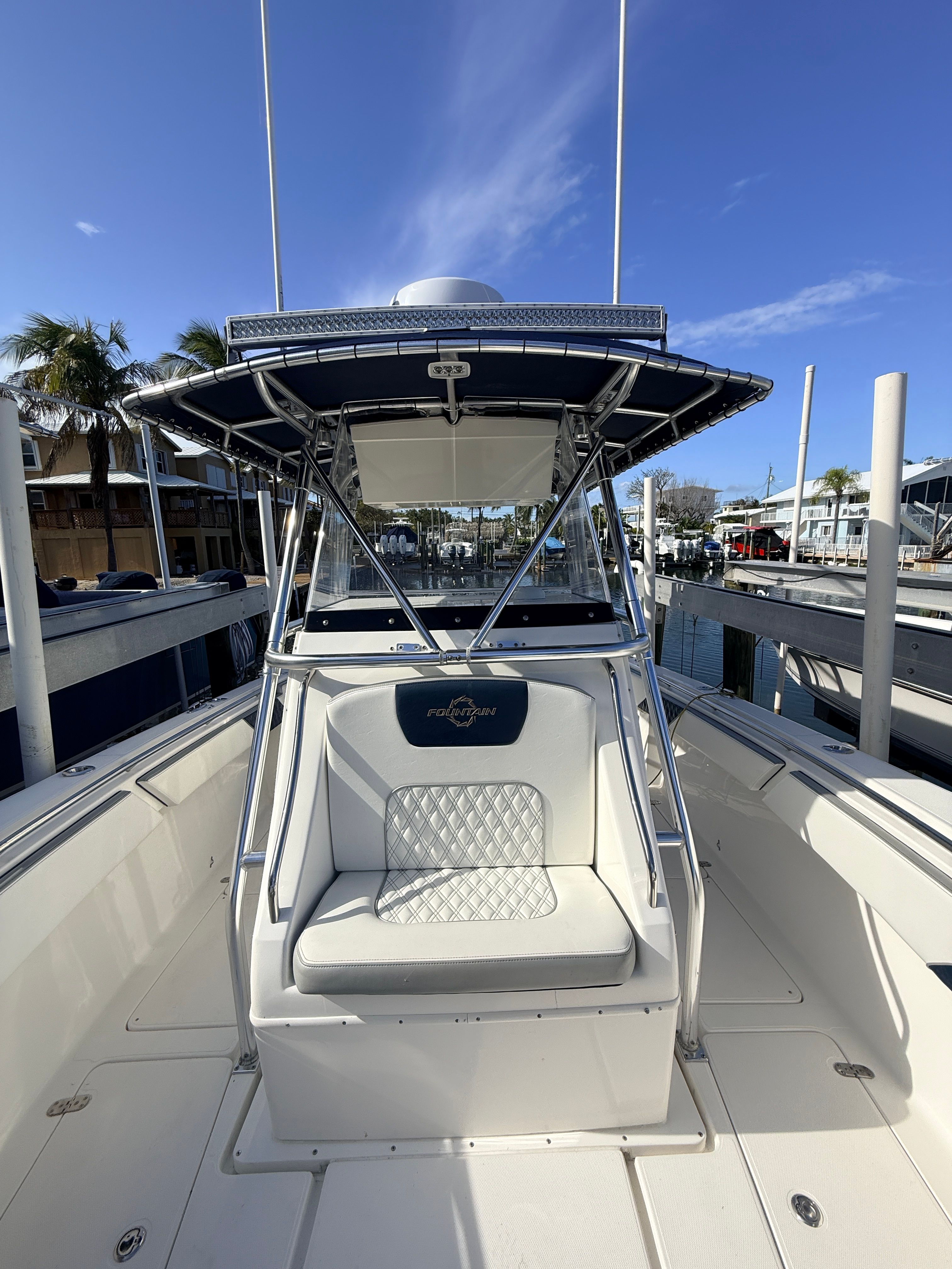 2007 Fountain 32 Center Console boat at dock, blue sky.