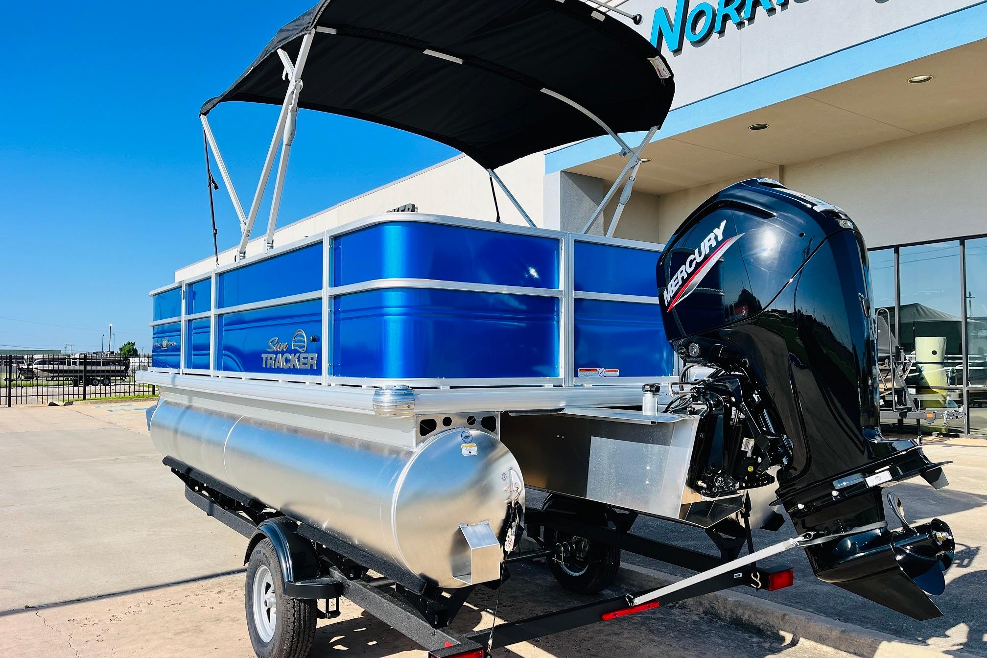 2026 Sun Tracker Party Barge 18 DLX pontoon boat with Mercury engine, parked outdoors.