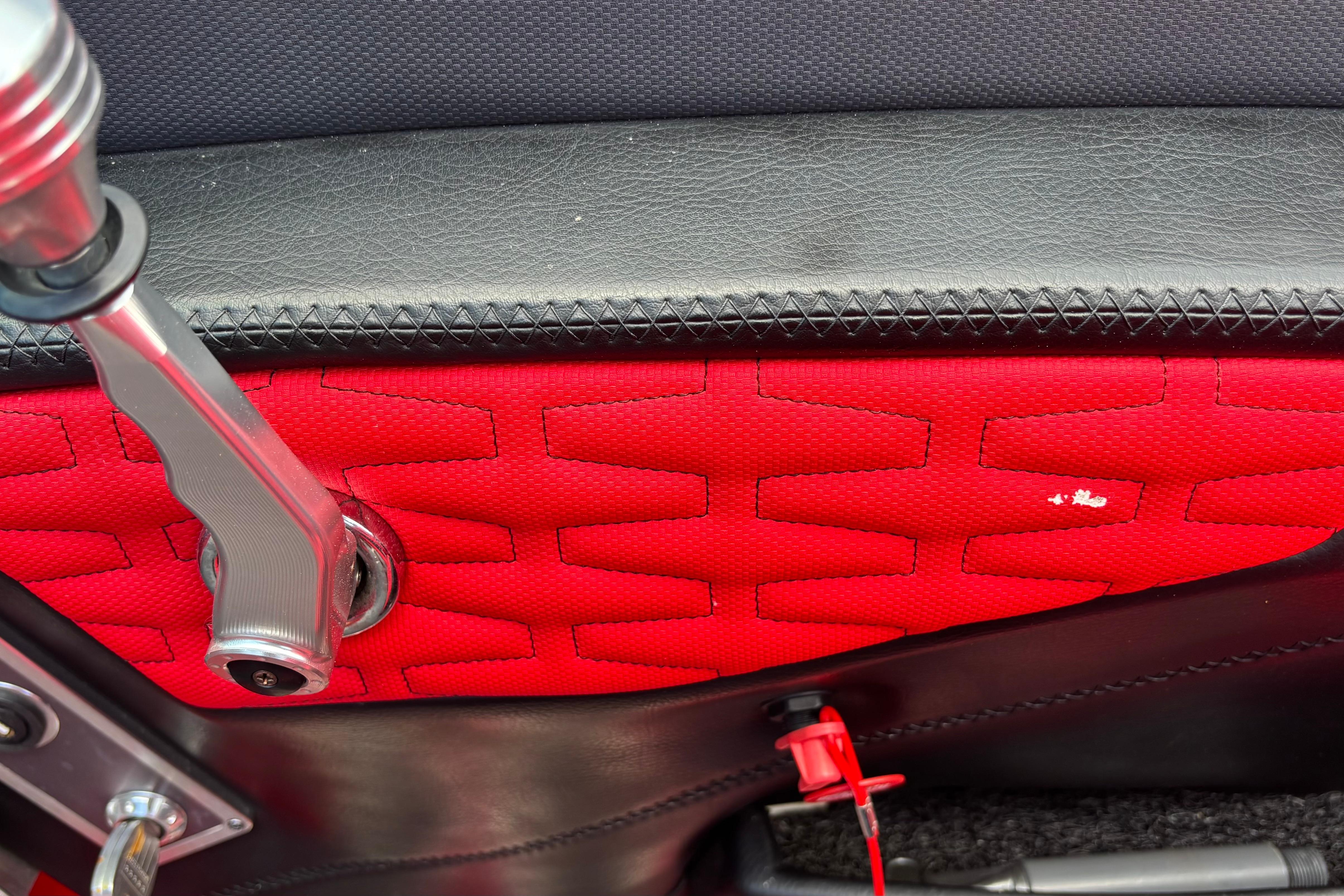 Close-up of 2020 MasterCraft X24 interior, featuring red and black upholstery with metal handle.