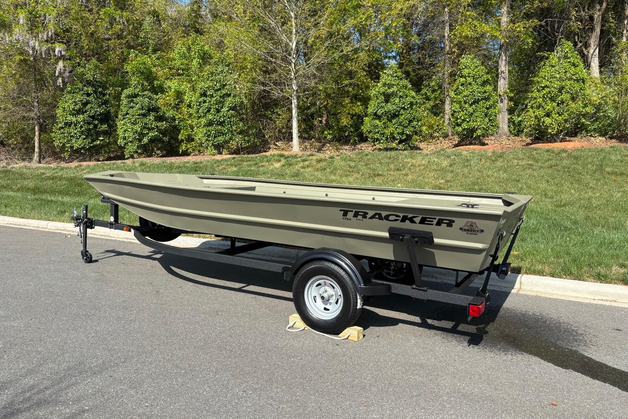 2026 Tracker Grizzly 1754 Utility boat on trailer, parked on a sunny road.