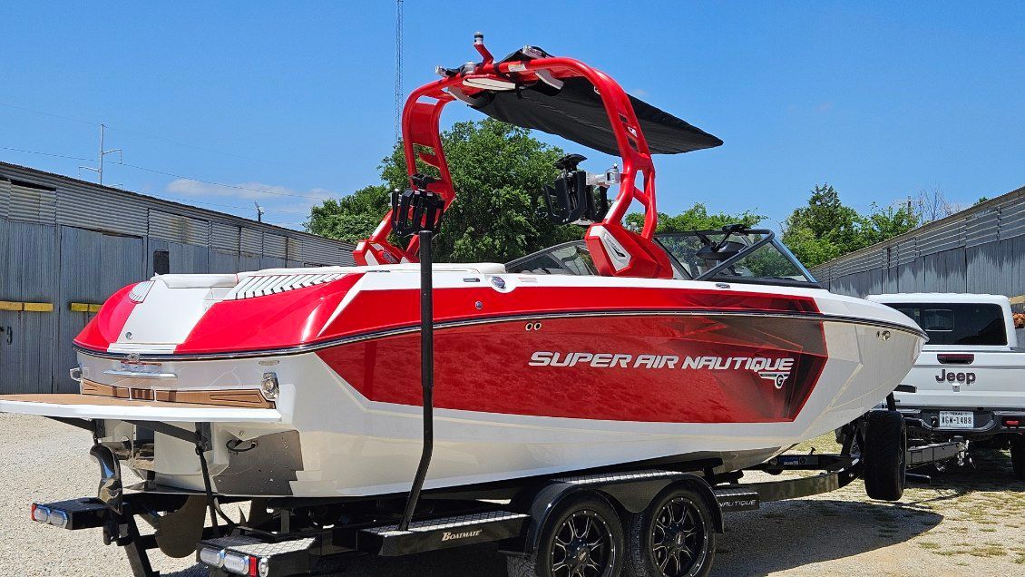A red and white boat on a trailer, featuring a prominent tower.