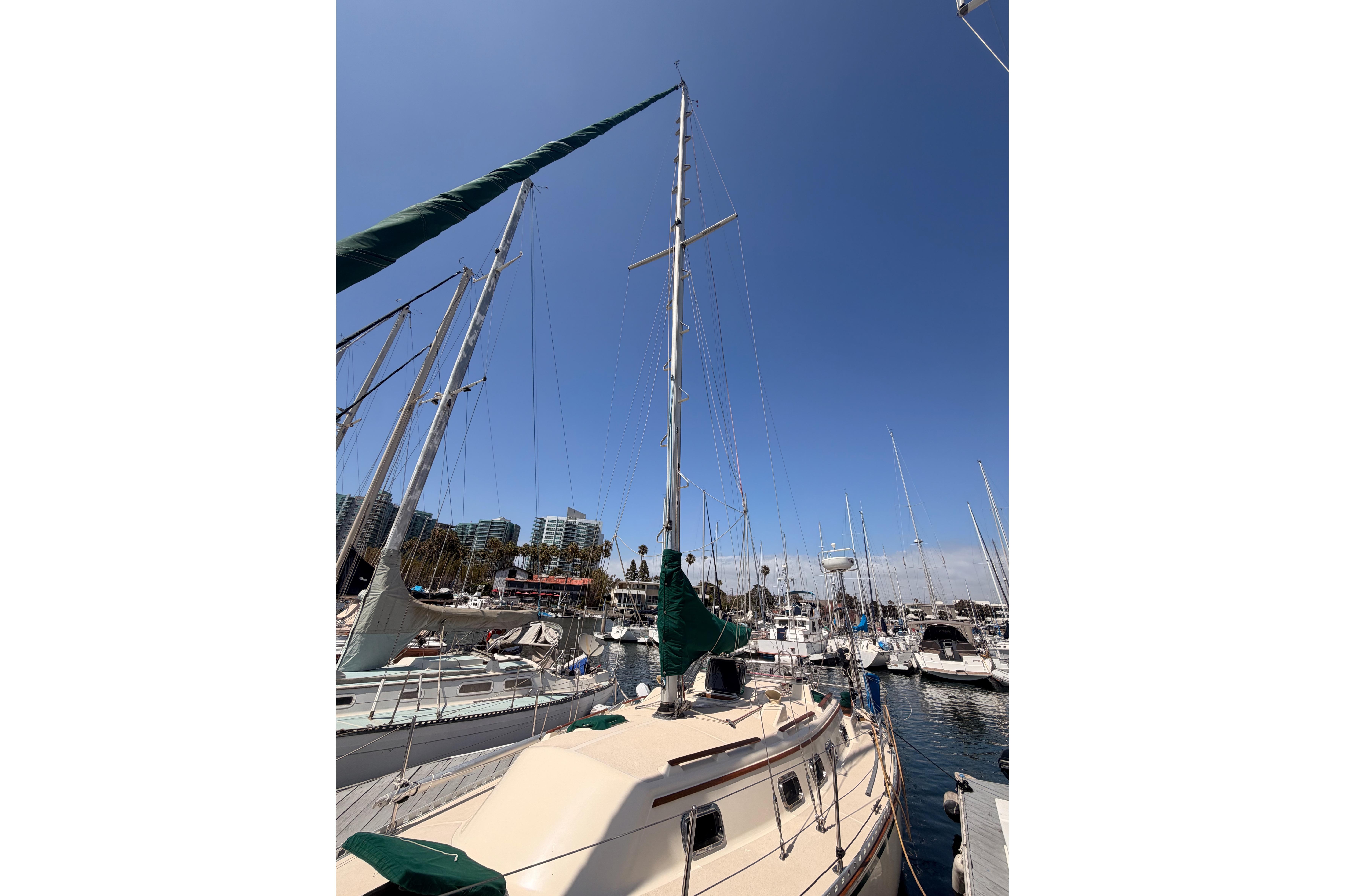 Sailboat docked in marina, Caliber 33 model, 1991, under clear blue sky.