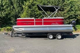 2026 Sun Tracker Party Barge 20 DLX pontoon boat with red exterior, parked on a trailer.