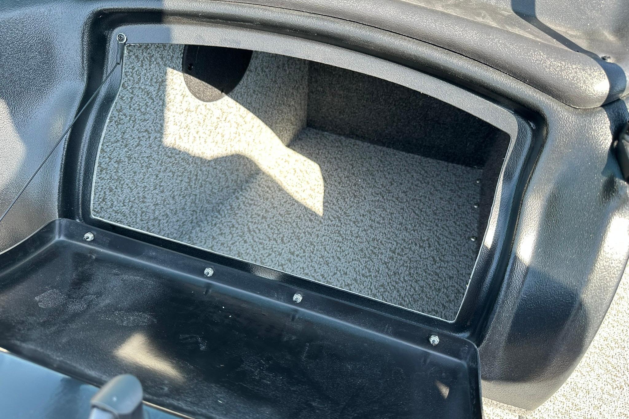 2026 Lund 1875 Fisherman boat storage compartment with carpeted interior.