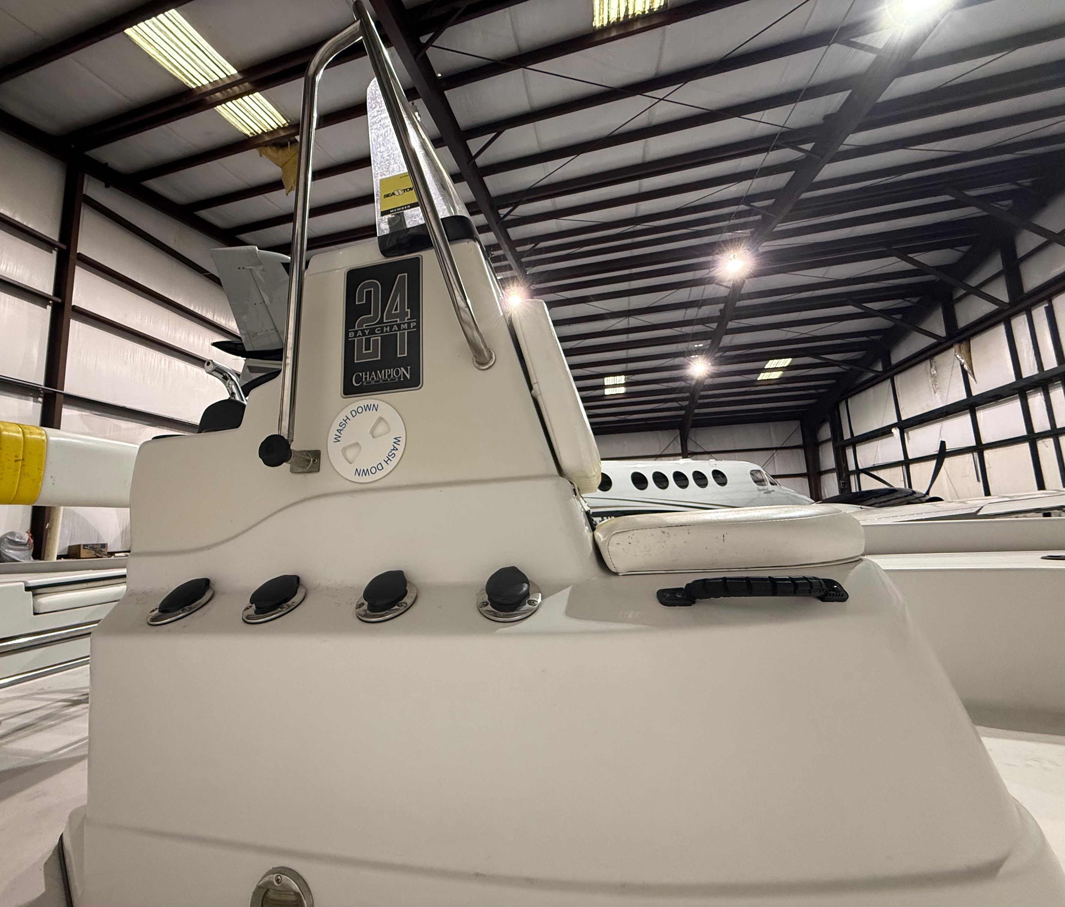 The image shows the cockpit of a Champion 24 Bay Champ boat in a warehouse.