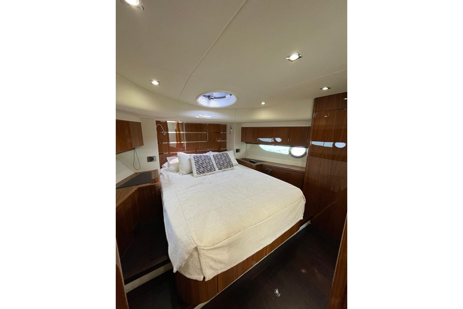 Luxurious bedroom interior of 2016 Sunseeker Manhattan 65 yacht with elegant wood finishes.