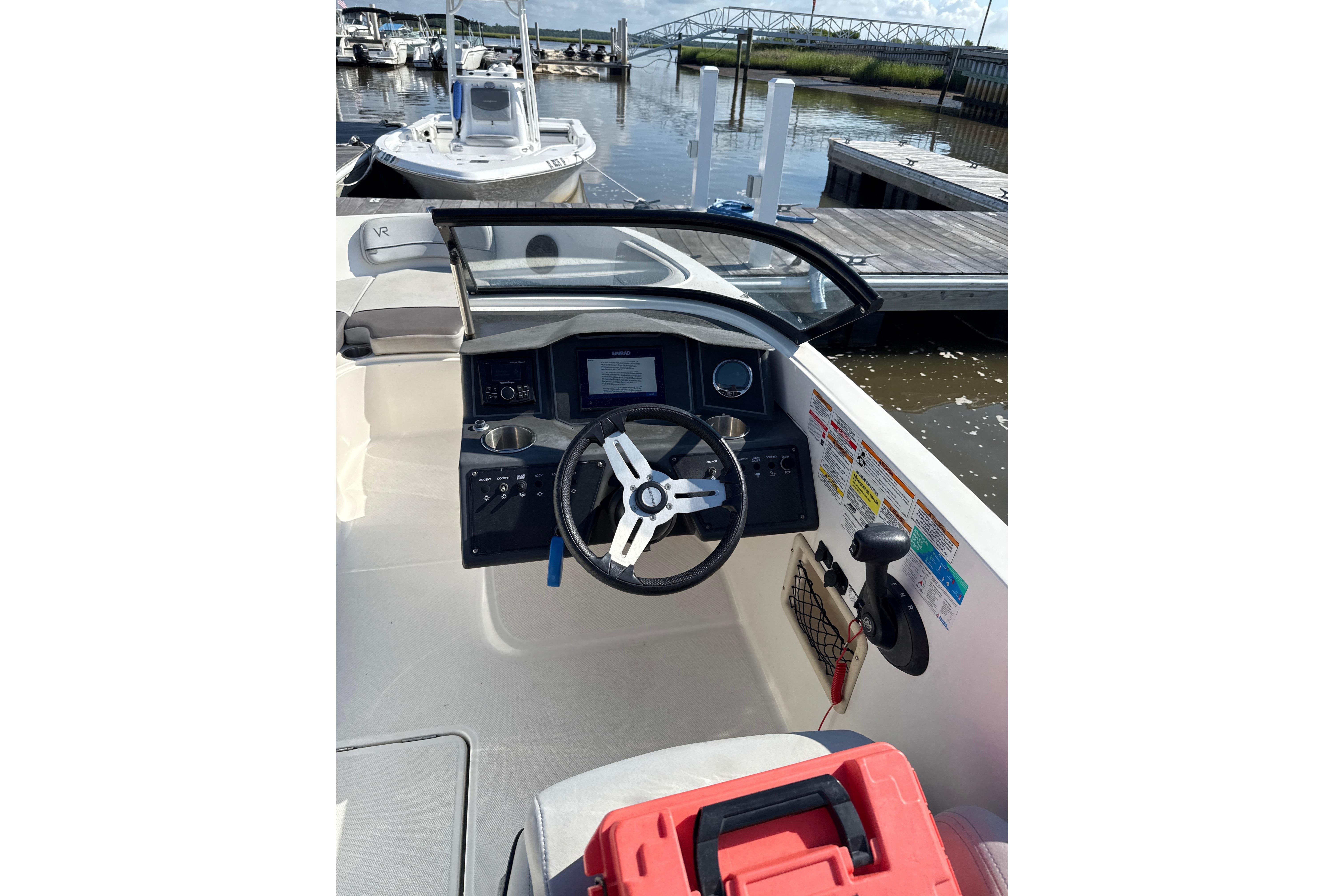 2023 Bayliner VR6 Bowrider OB cockpit with steering wheel and control panel at marina.