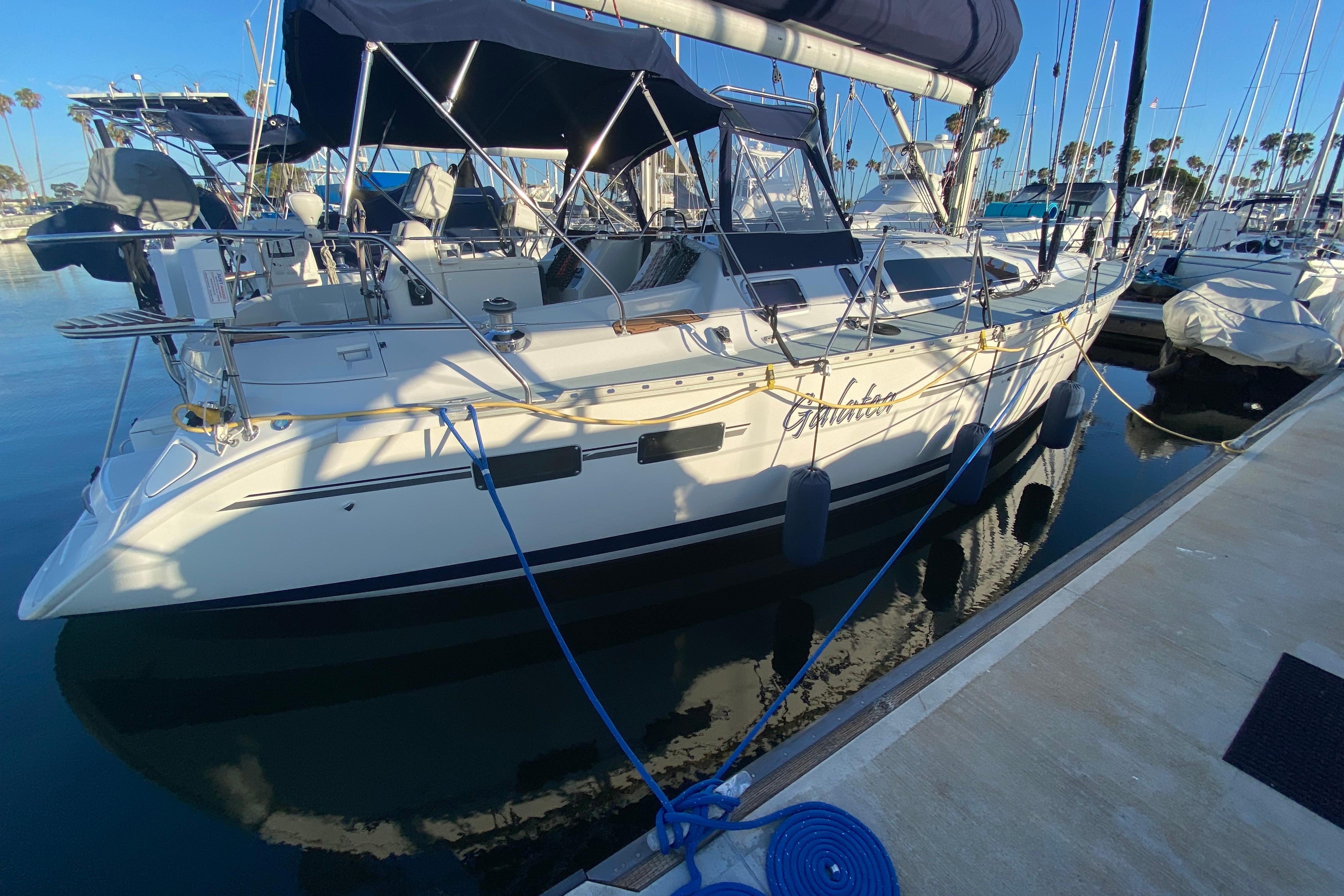 1997 Hunter Legend 40.5 sailboat docked at marina, featuring sleek design and blue canopy.