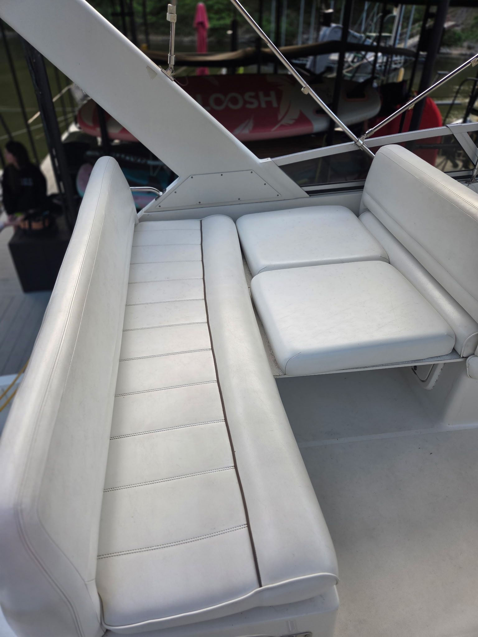 White cushioned seating on a boat, surrounded by railings and a covered area.