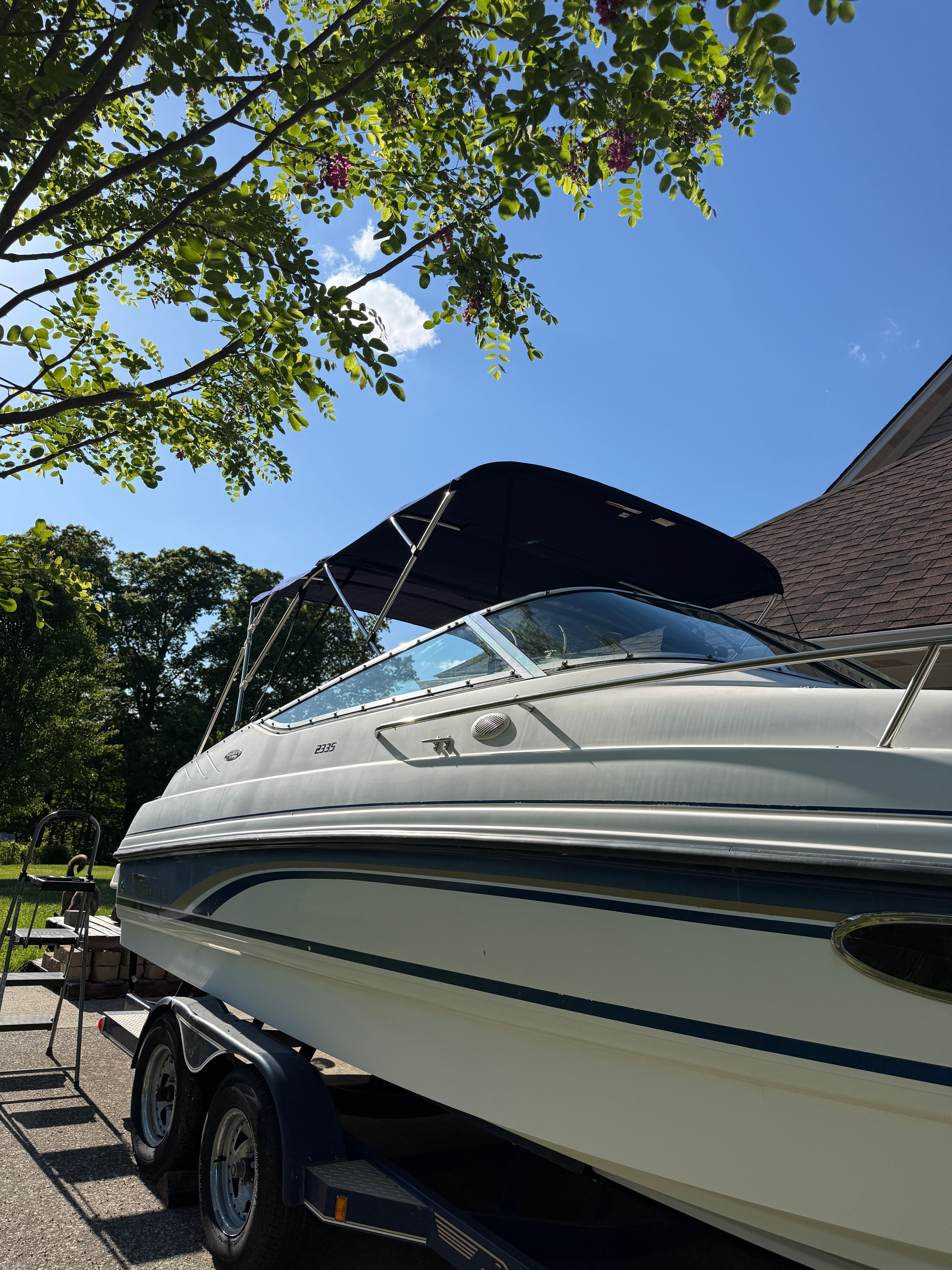 1999 Custom 2335 Cuddy Cabin boat on trailer under blue sky.