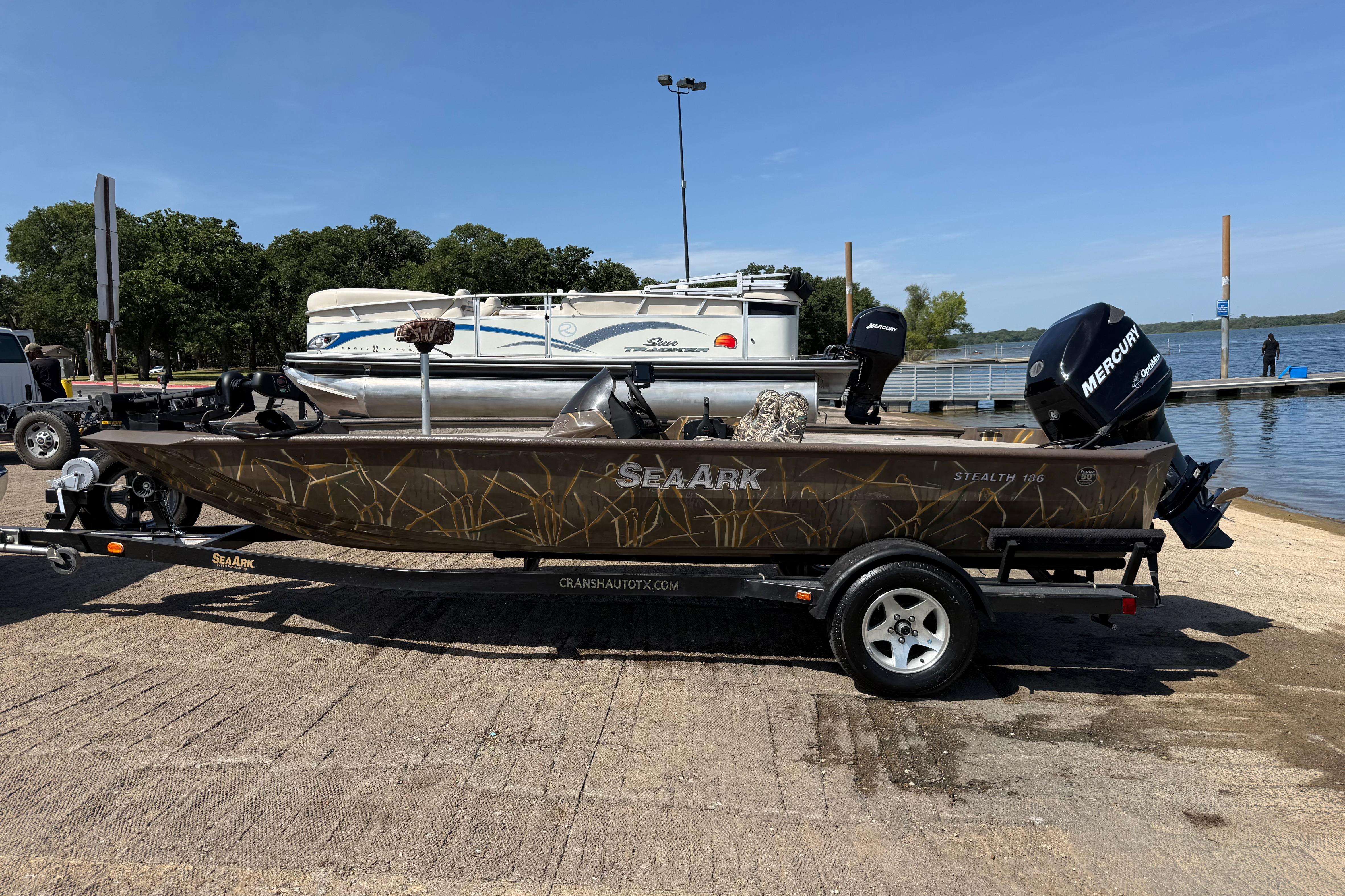 2010 SeaArk Stealth 190 boat on trailer by lake, featuring Mercury outboard motor.