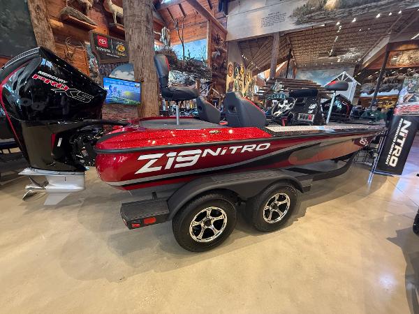 2025 Nitro Z19 boat in showroom, red and black design, dual-axle trailer.