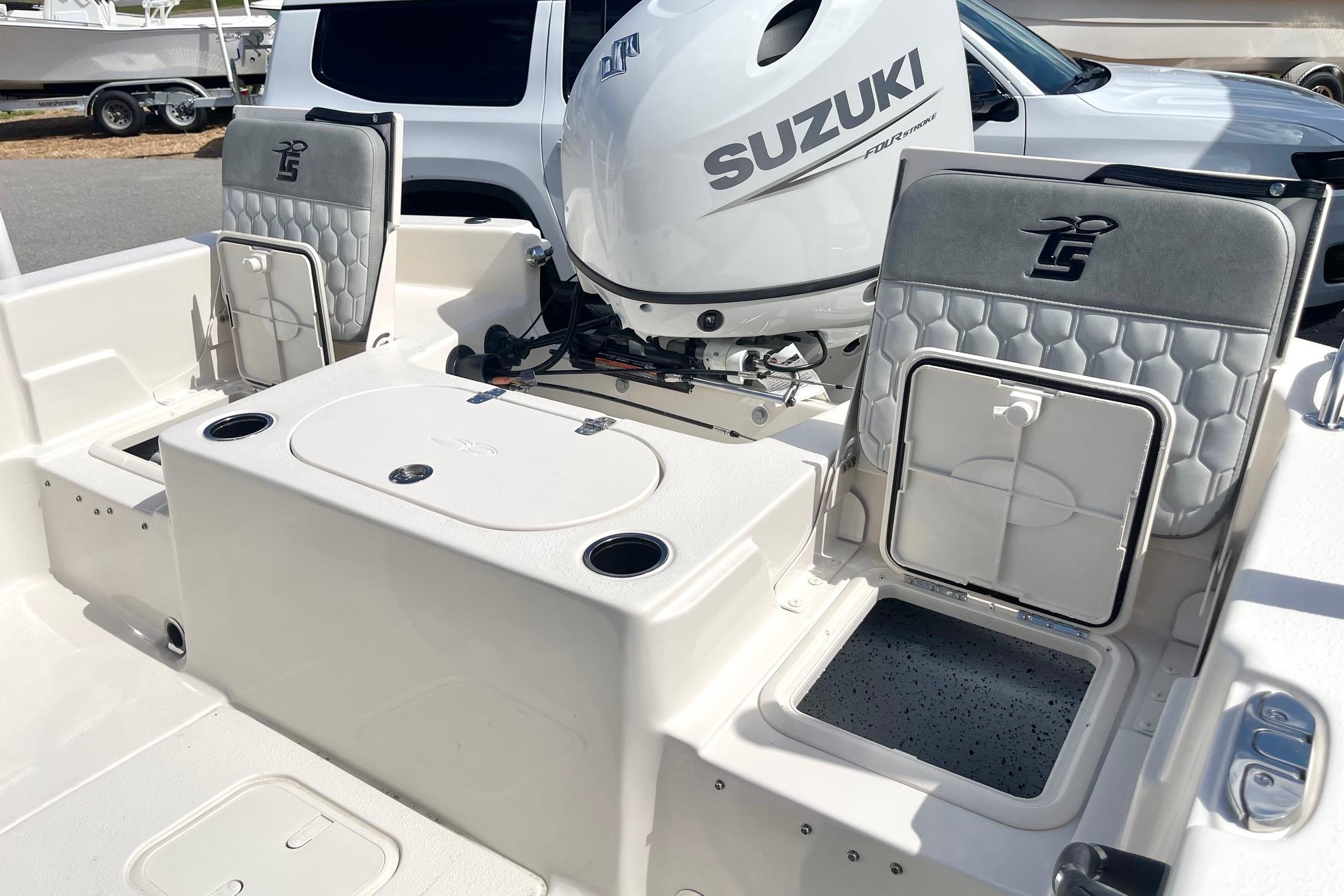 2026 Carolina Skiff 19 LS boat interior with Suzuki engine, featuring seating and storage compartments.