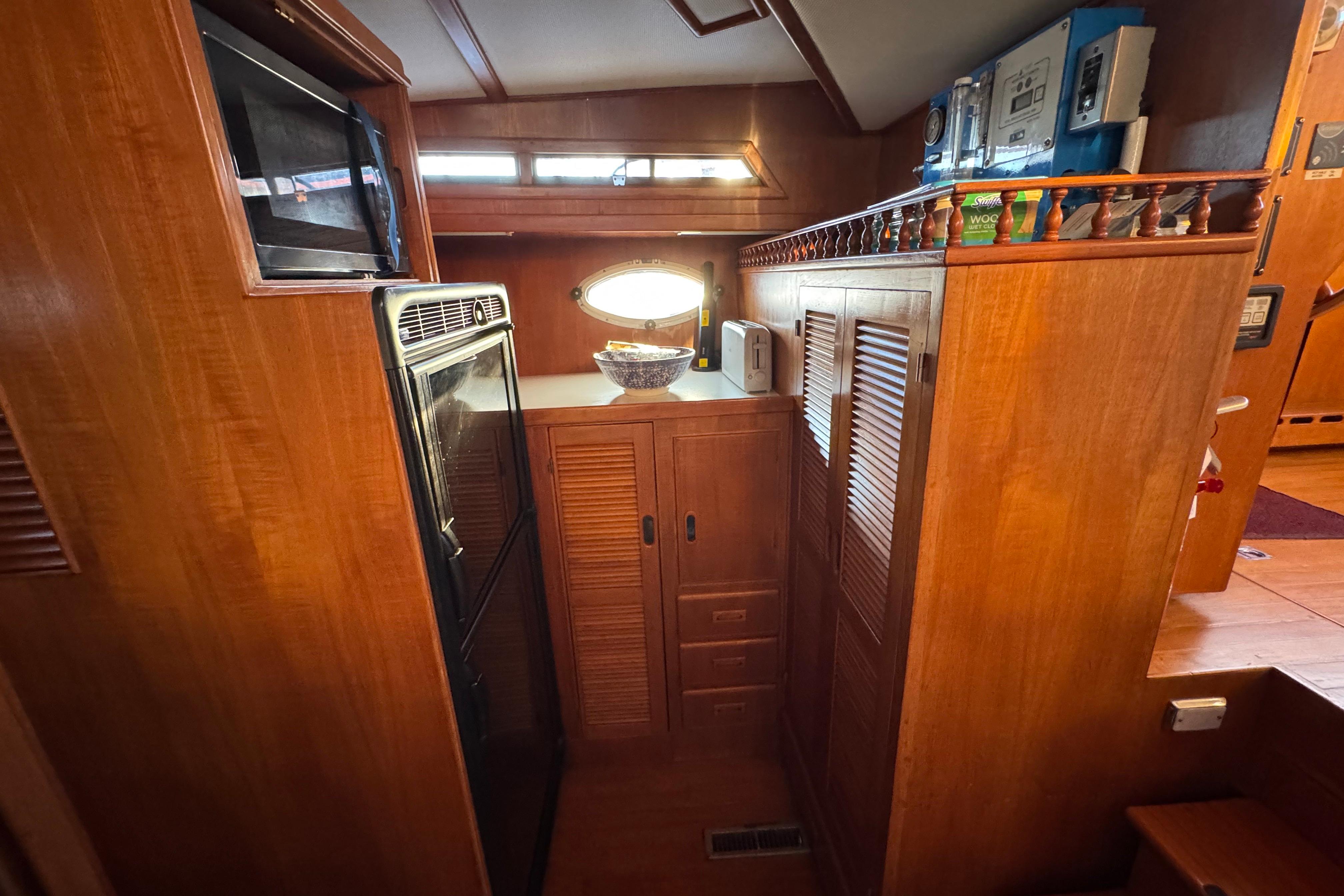 Cozy wooden interior of a 1987 President 37 yacht kitchen with appliances and storage.
