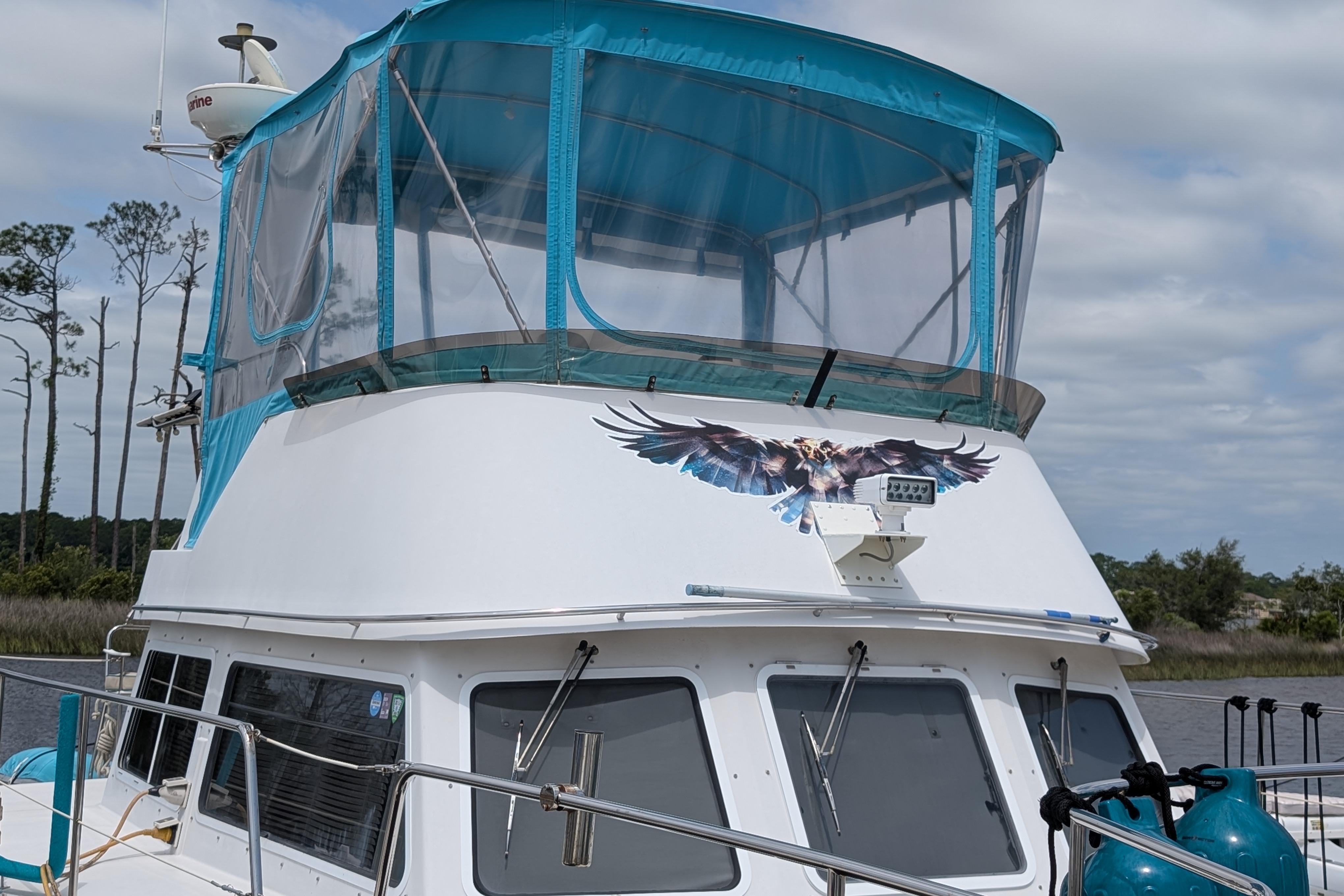 2004 PDQ 34 Powercat with blue canopy and eagle graphic on the water.