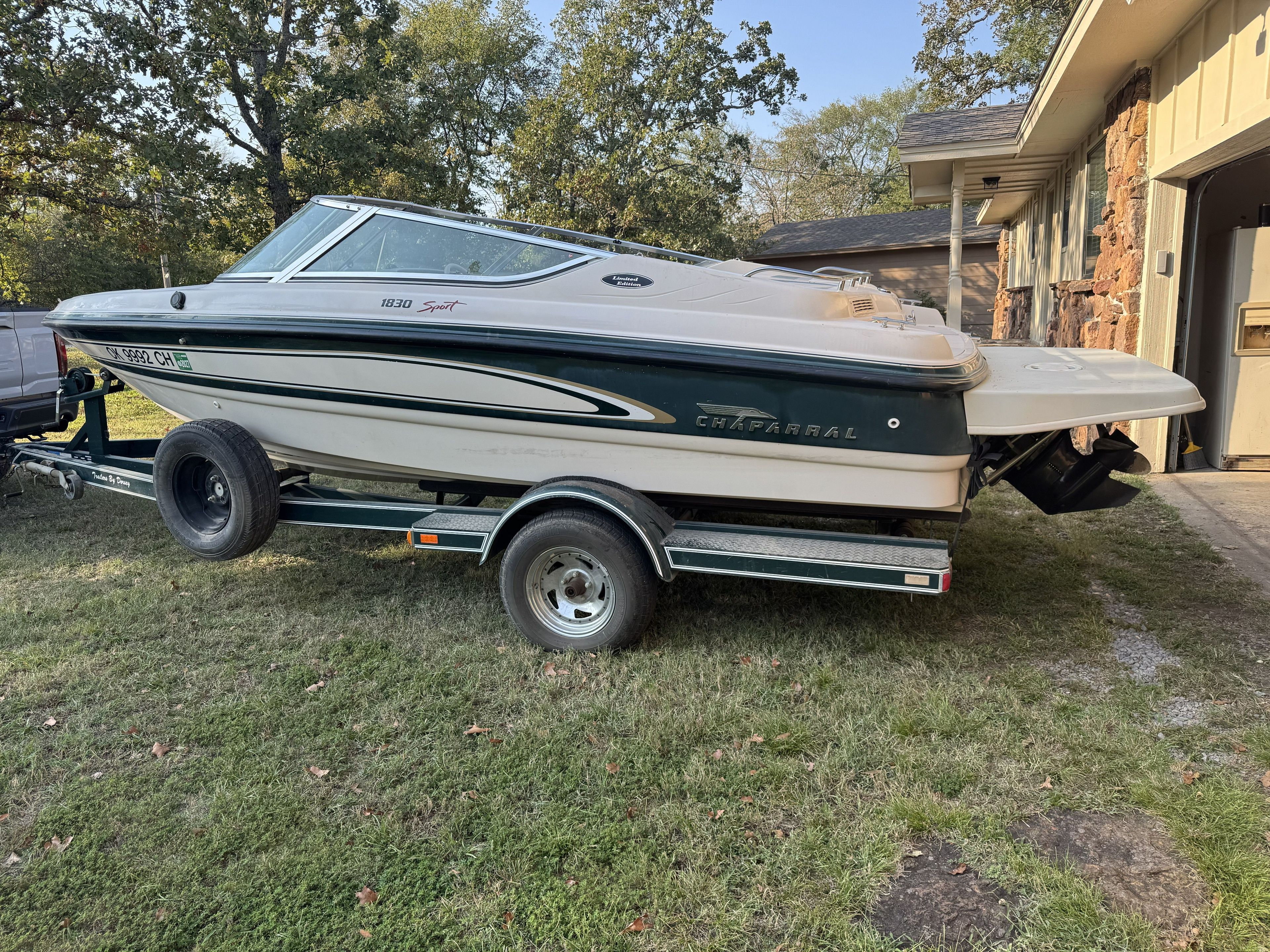 A 1996 Chaparral 1830 SS boat on a trailer beside a house.