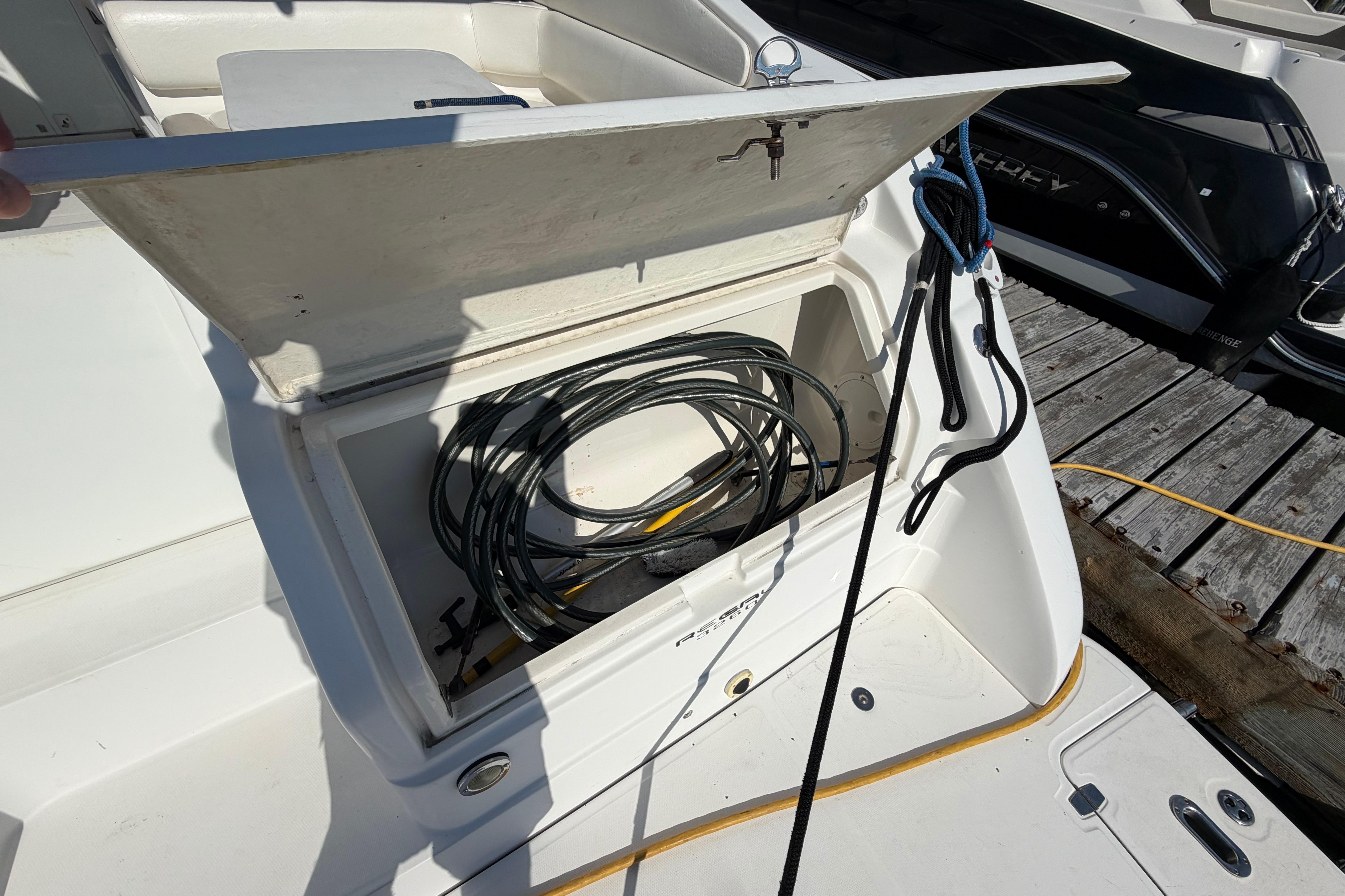 Open storage compartment on 2003 Regal Commodore 3260 boat with coiled cables inside.