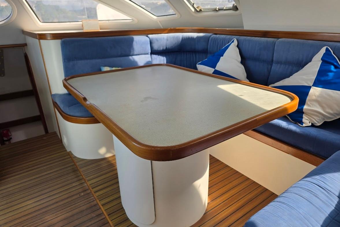 Cozy interior of 2003 Outremer 45 yacht with blue seating and wooden table.