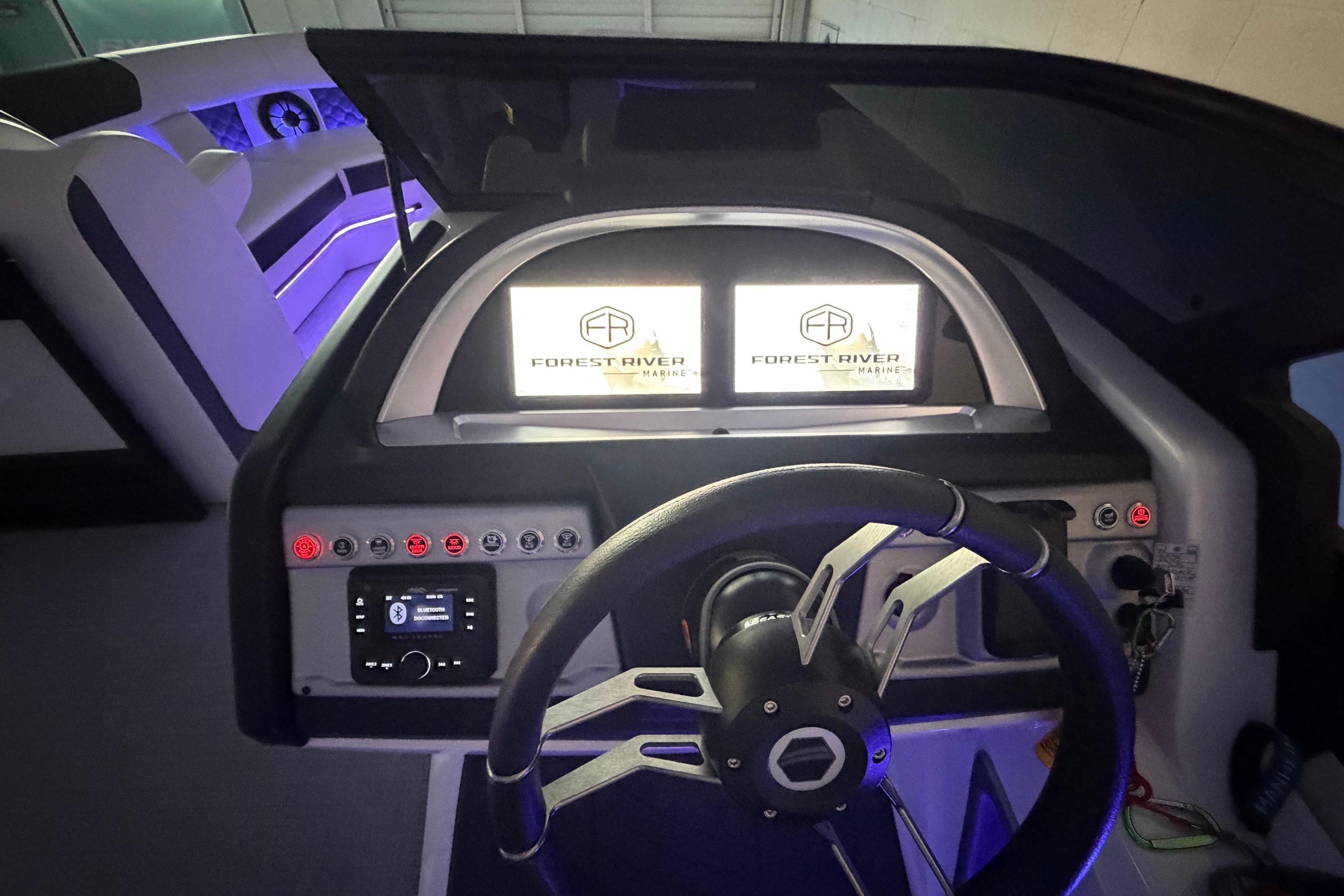 Interior dashboard of 2026 South Bay 525SB2 boat with illuminated controls and steering wheel.