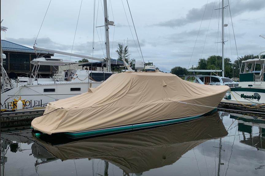 Covered 2004 RB DERELI Daytripper 40 boat docked in a marina.