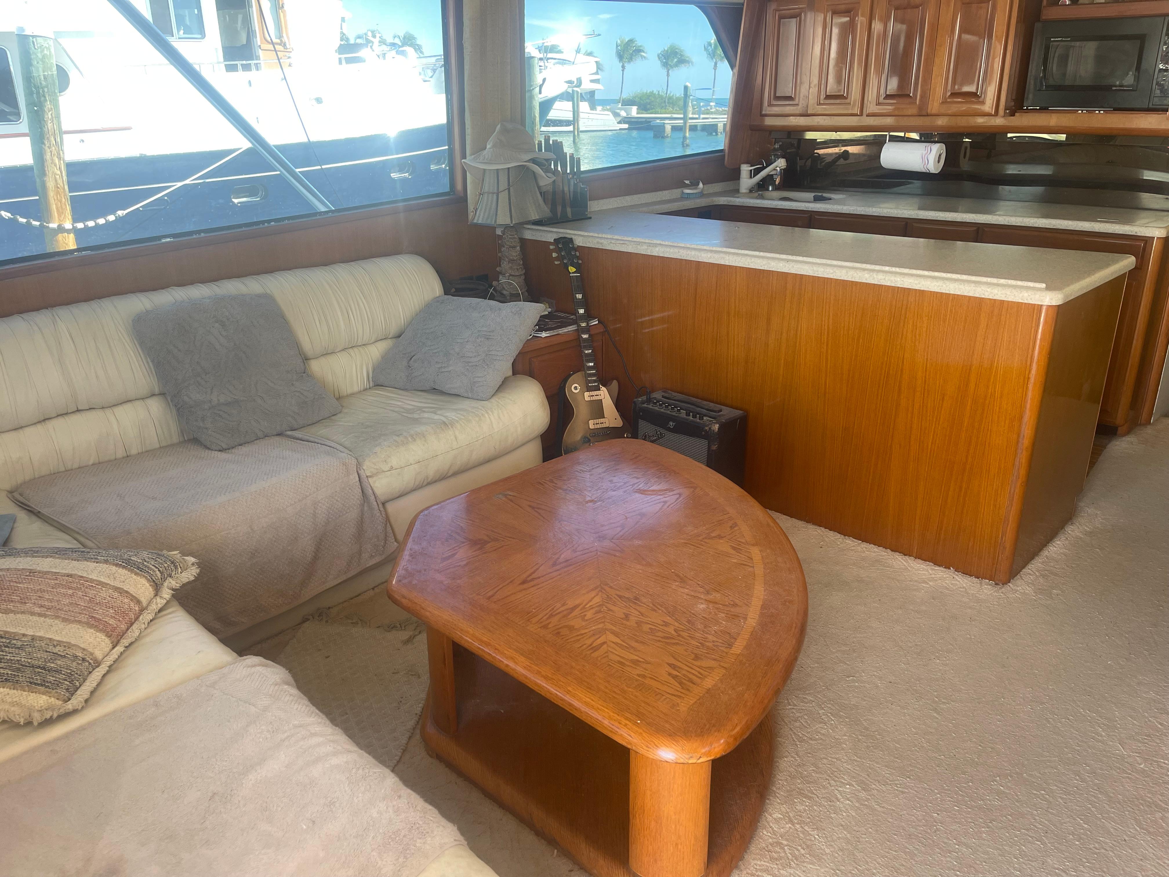 Cozy interior of 1999 Viking 58 EB yacht with sofas, guitar, and wooden table.