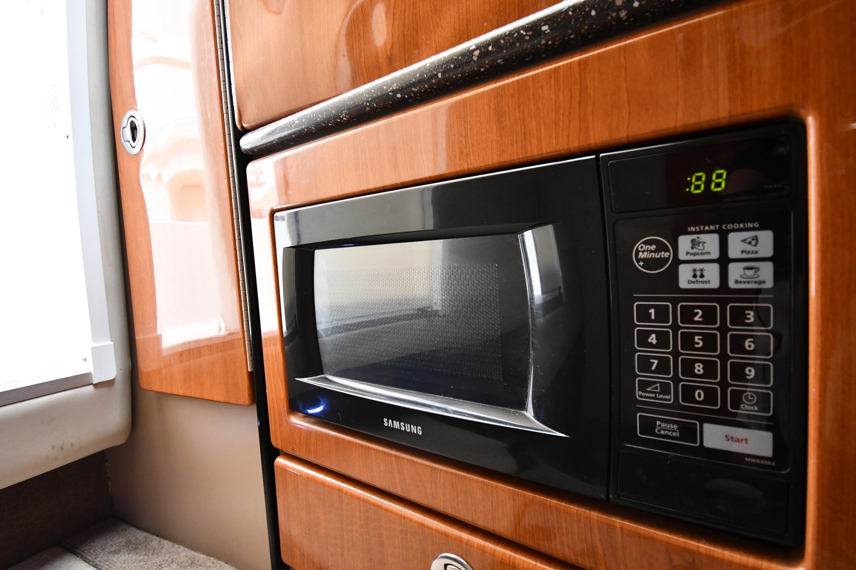 Microwave in 2004 Formula 330 Sun Sport boat interior, featuring wood paneling and digital controls.