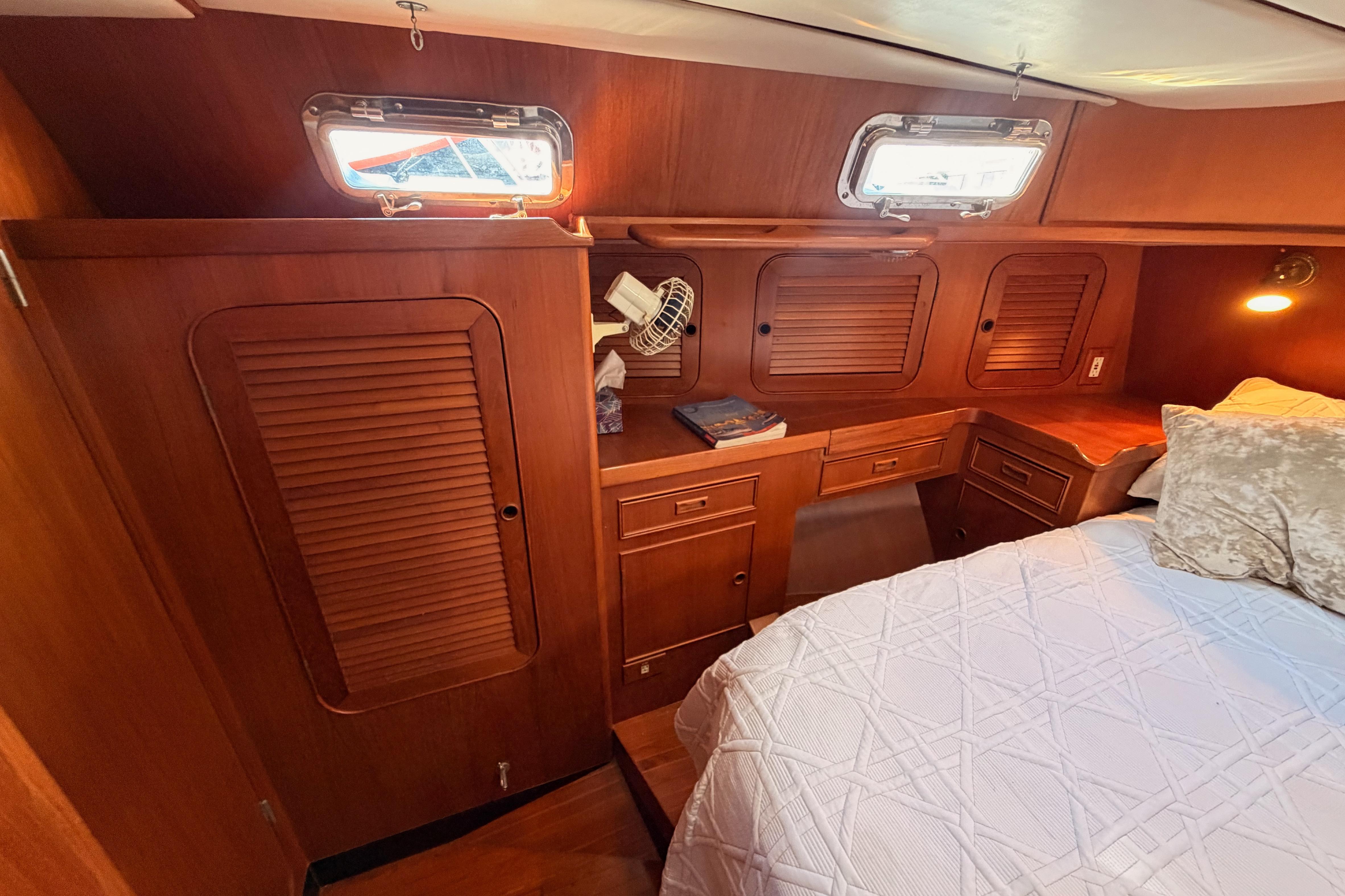 Cozy cabin interior of a 1991 Hylas 51 yacht with wooden cabinetry and bedding.