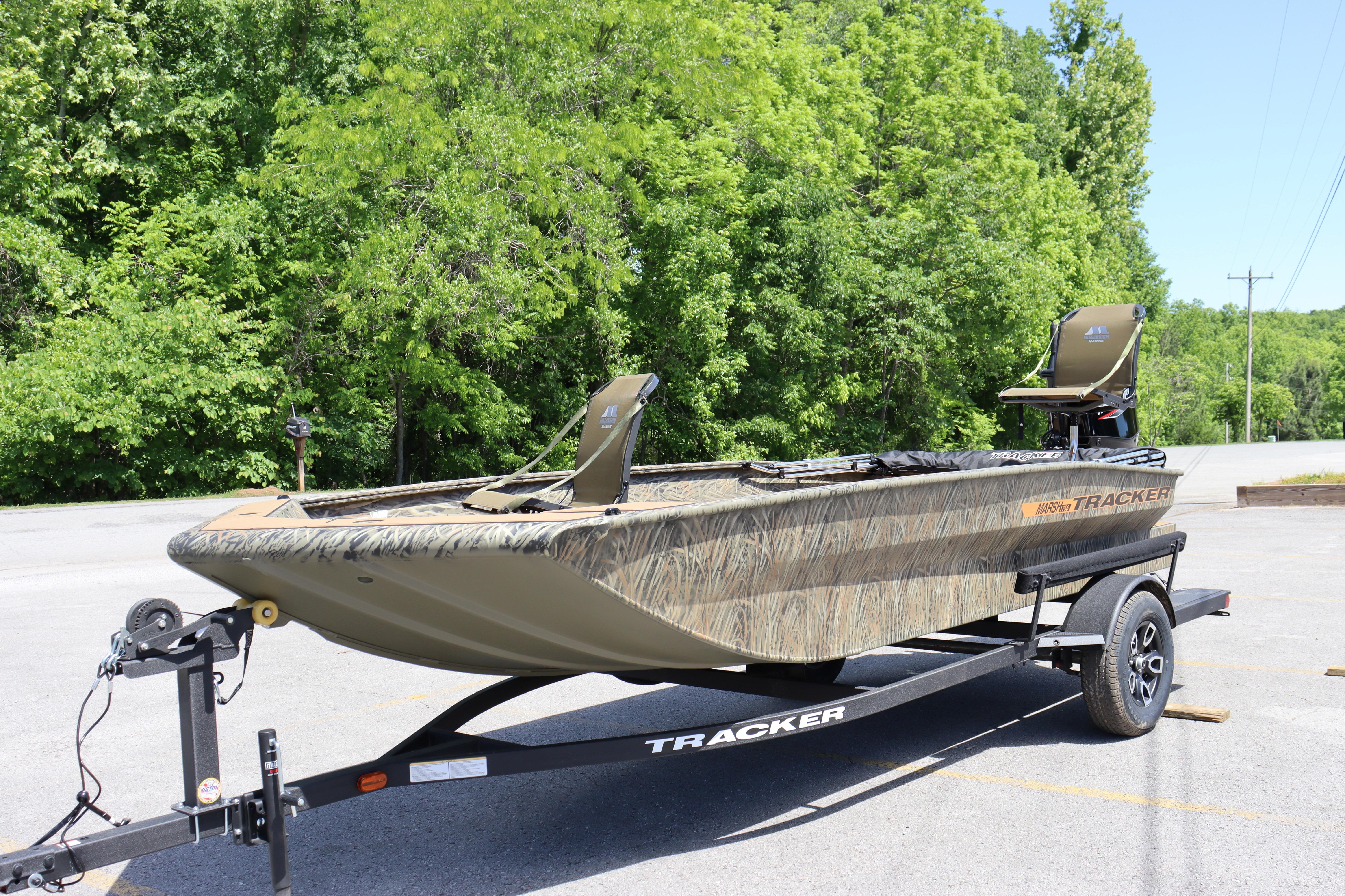 2026 Tracker Grizzly 1756 T Marsh boat on trailer, parked near lush green trees.