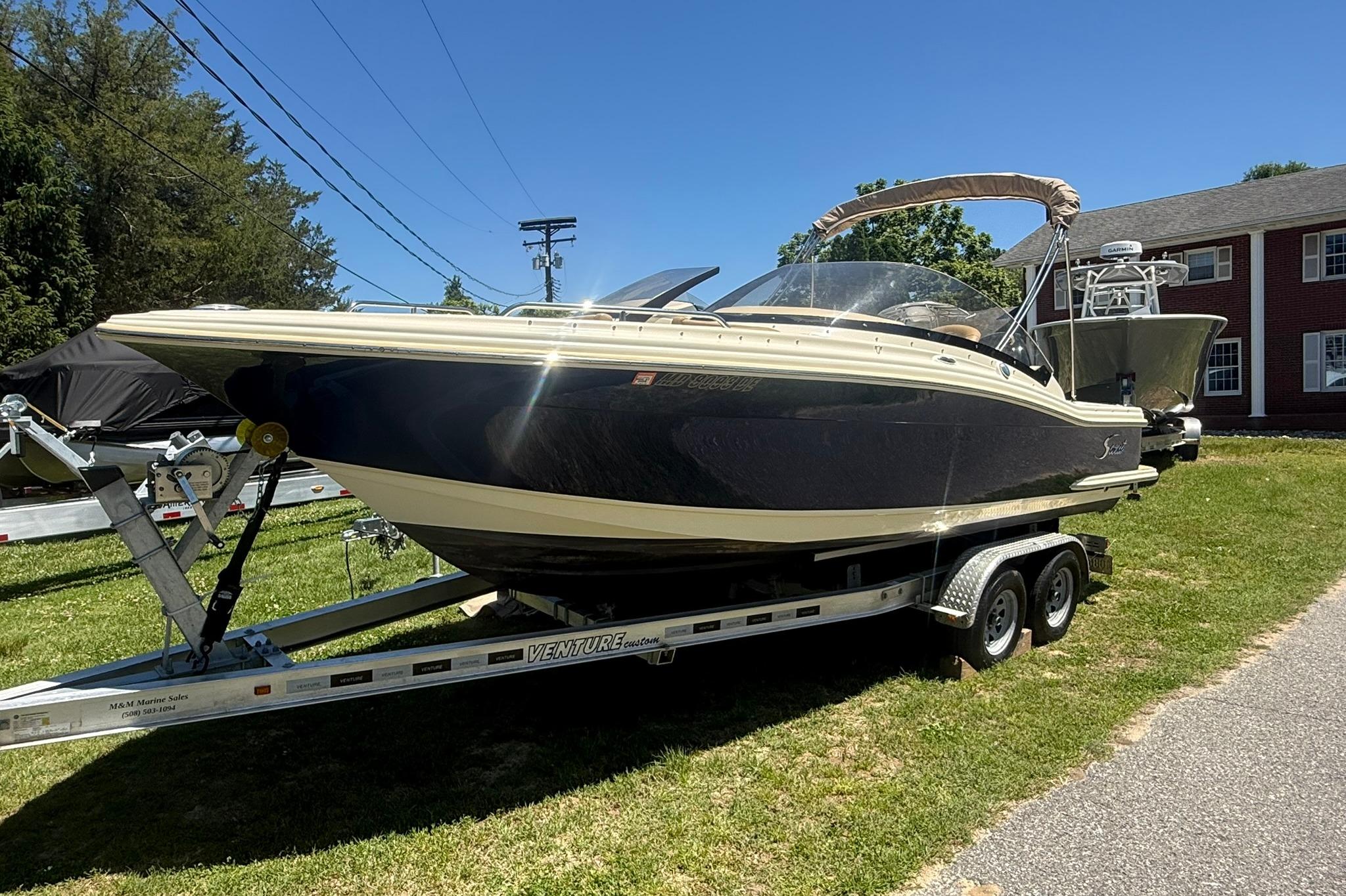 2021 Scout 215 Dorado boat on trailer, parked on grass under clear blue sky.