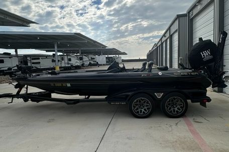A black 2023 Skeeter FXR21 Apex boat on a trailer in a storage area.
