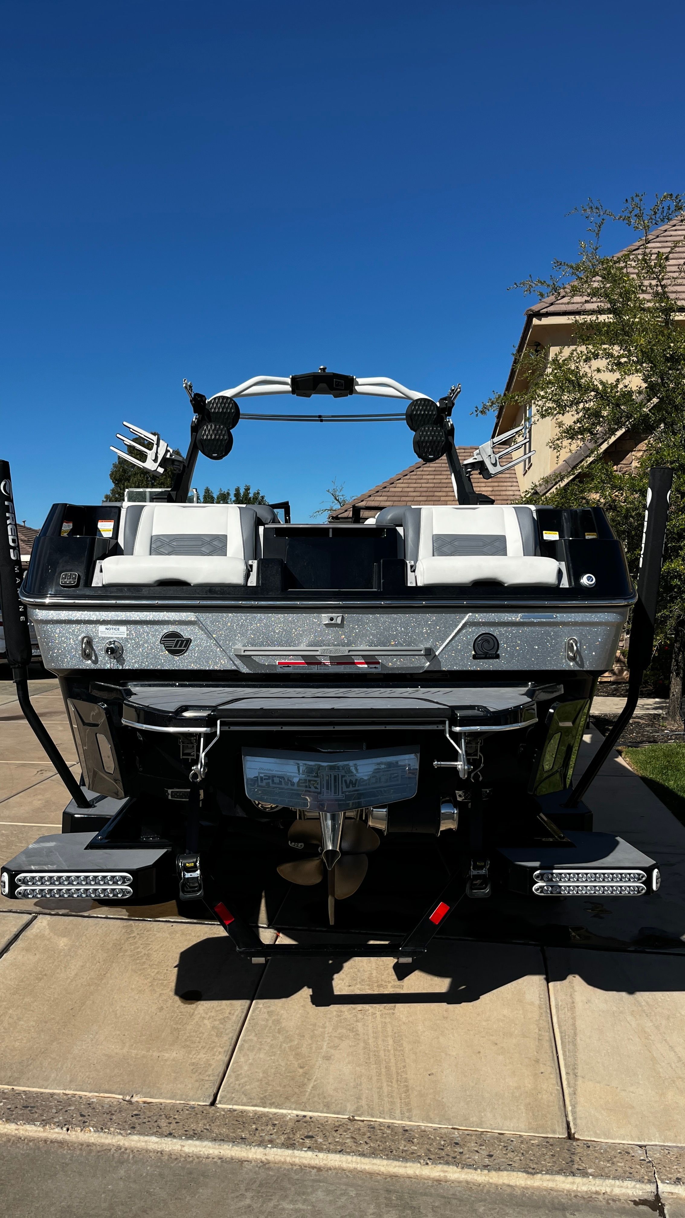 The image shows a 2023 Malibu Wakesetter 26 LSV boat on a trailer in a driveway.