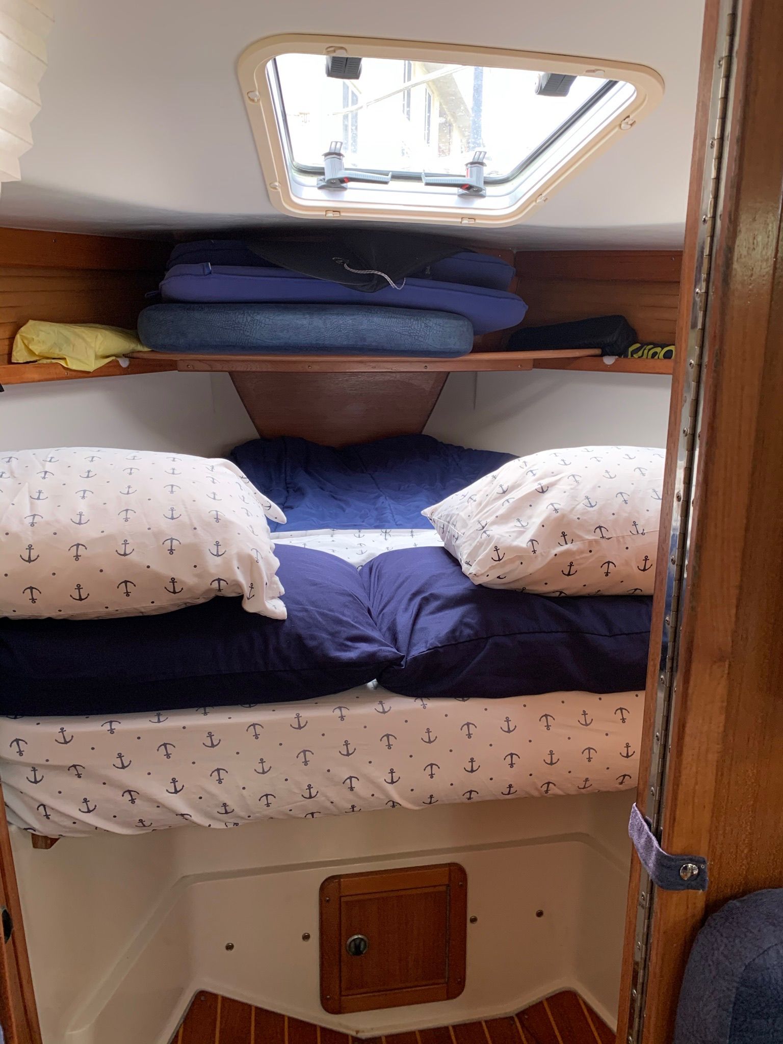 A cozy boat bedroom with a bed dressed in anchor-patterned bedding.