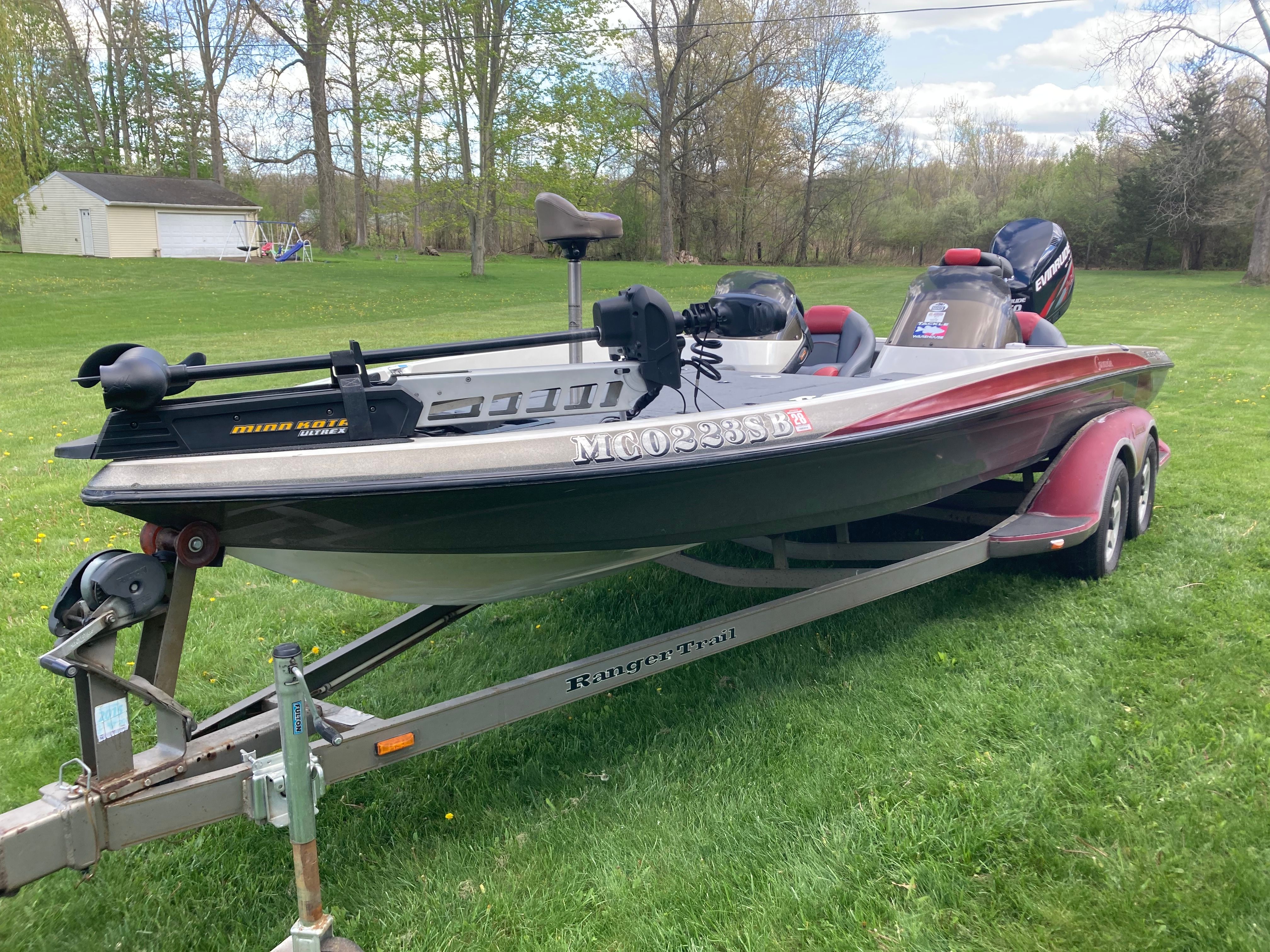 A 2002 Ranger 522DVX Comanche boat on a trailer, parked on a grassy lawn.