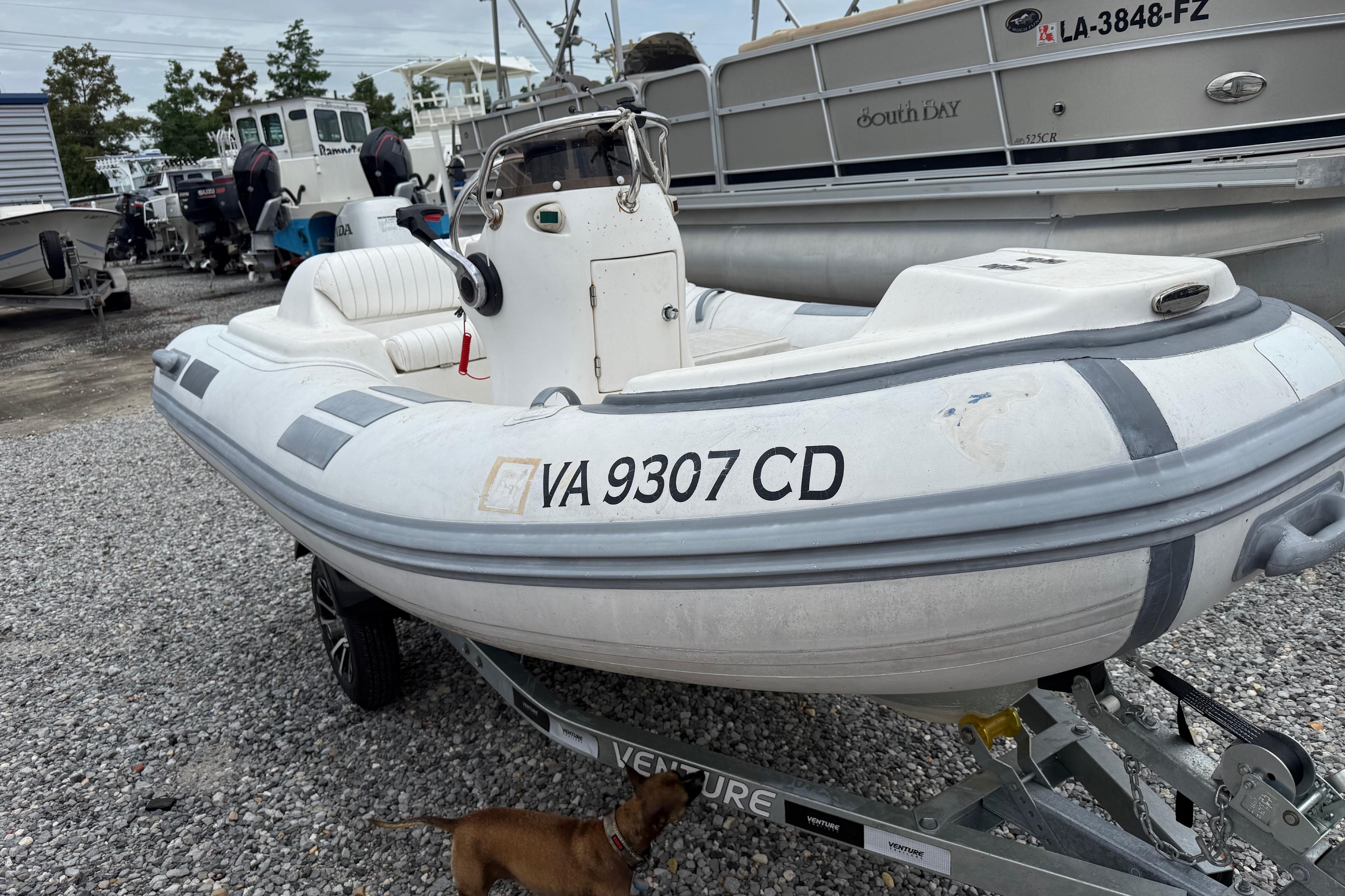 Inflatable boat on trailer, Caribe DL-11, 2008 model, parked on gravel with other boats.